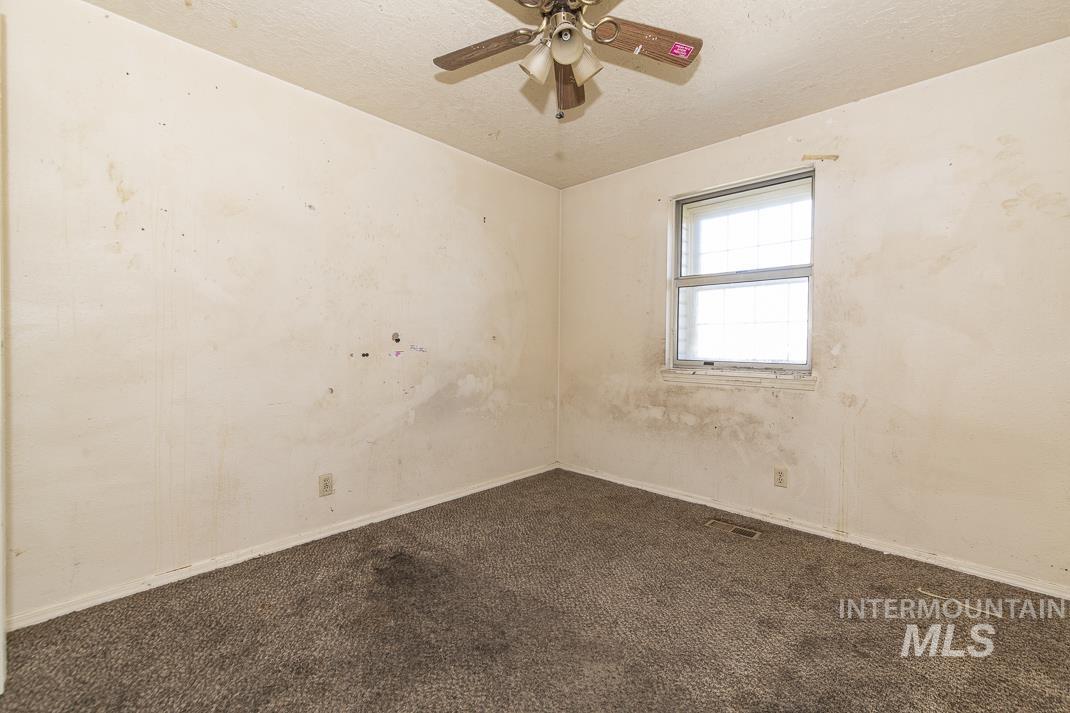 Unfurnished room with dark carpet, a ceiling fan, and a textured ceiling