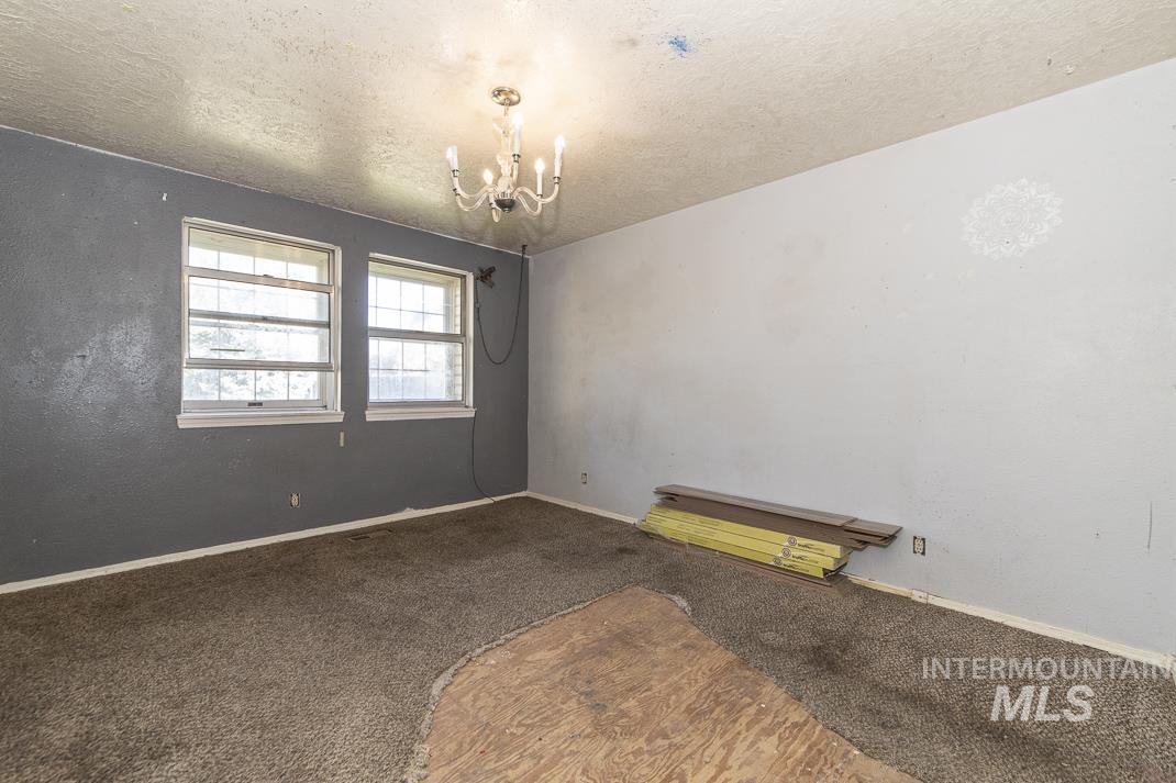Spare room with carpet, a textured ceiling, and a chandelier