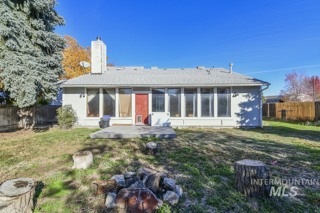 Rear view of house with a fenced backyard, roof with shingles, a chimney, and a patio area
