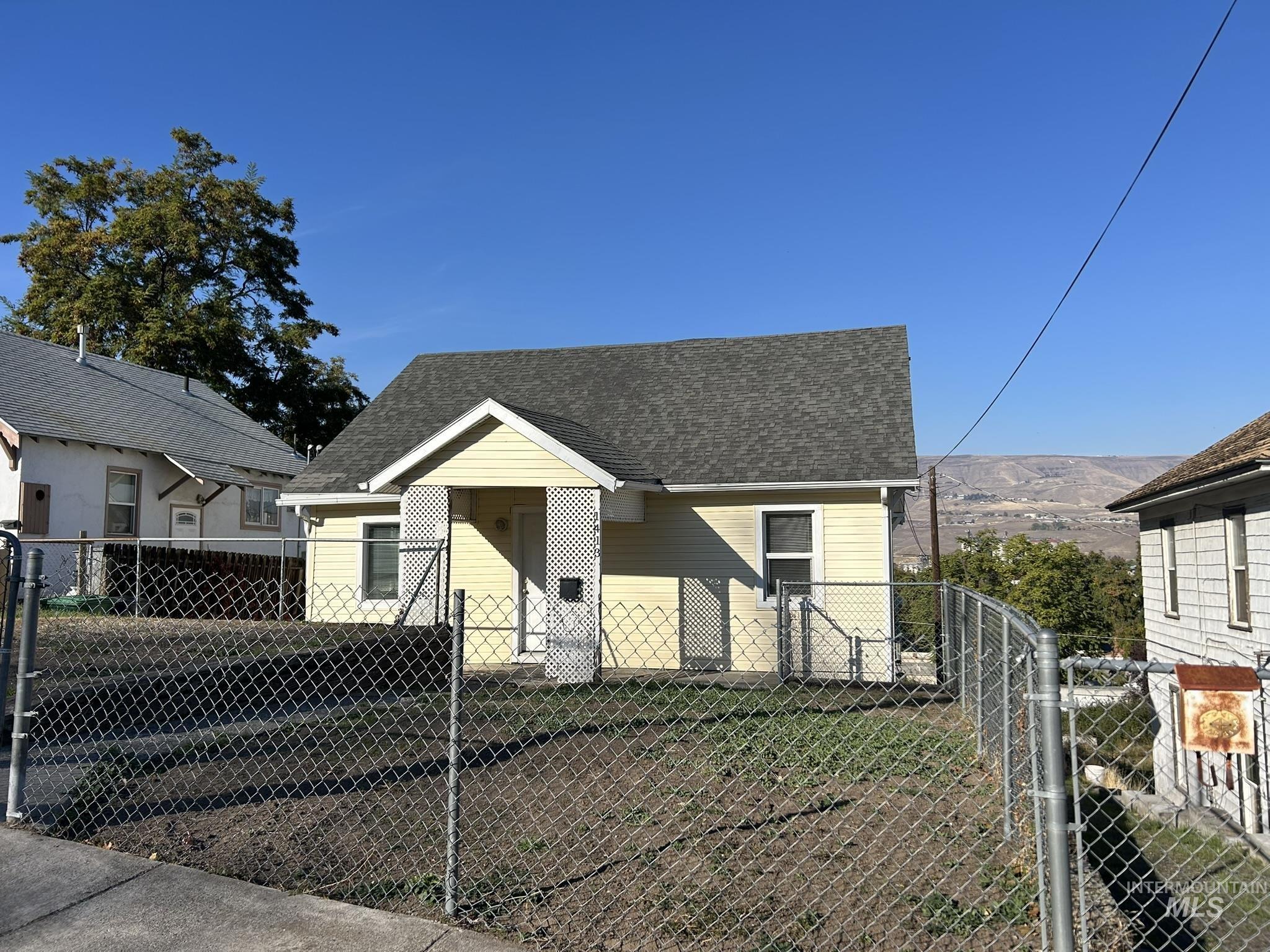 Bungalow with roof with shingles and a fenced front yard