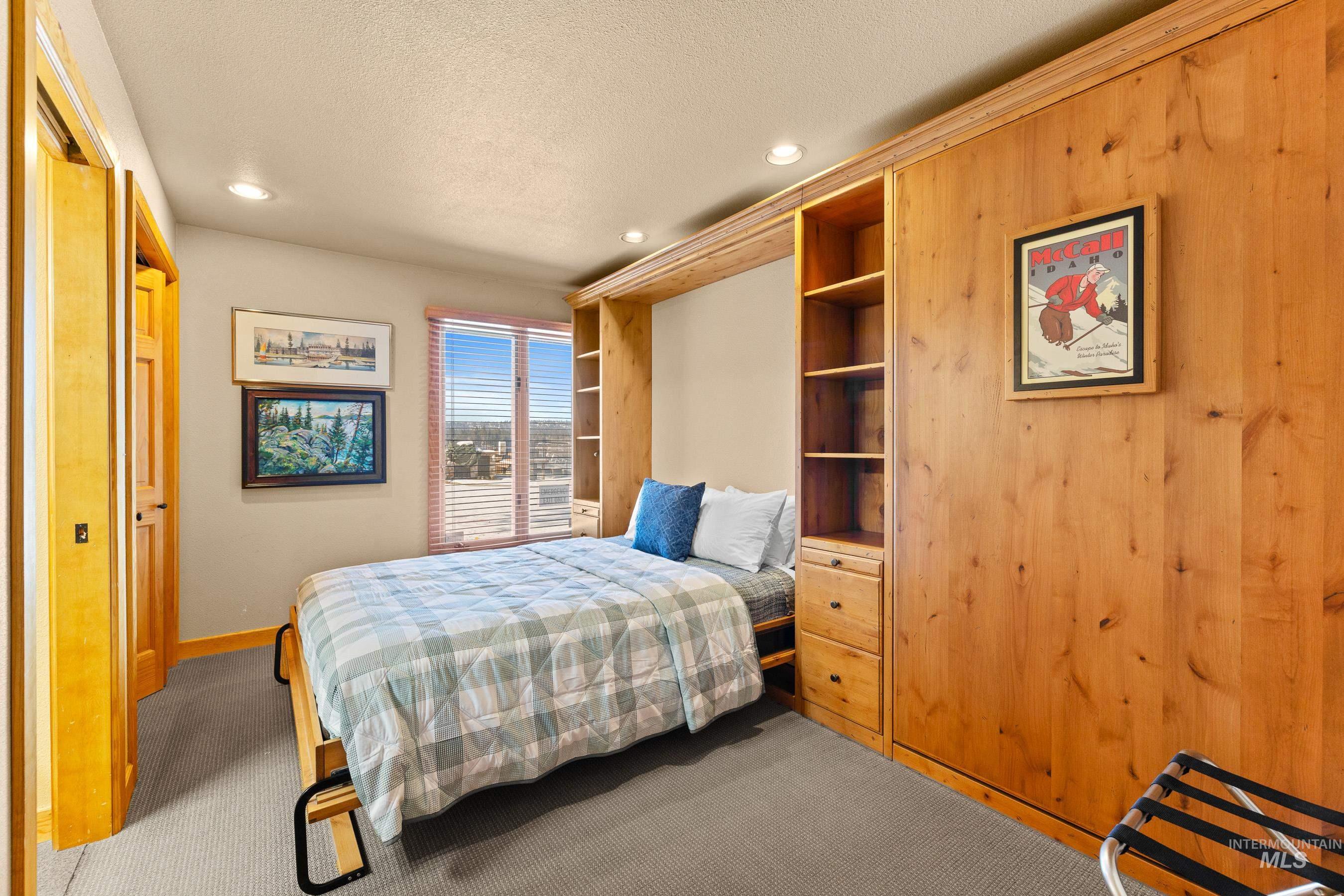 Bedroom featuring carpet, a textured ceiling, recessed lighting, and wood walls