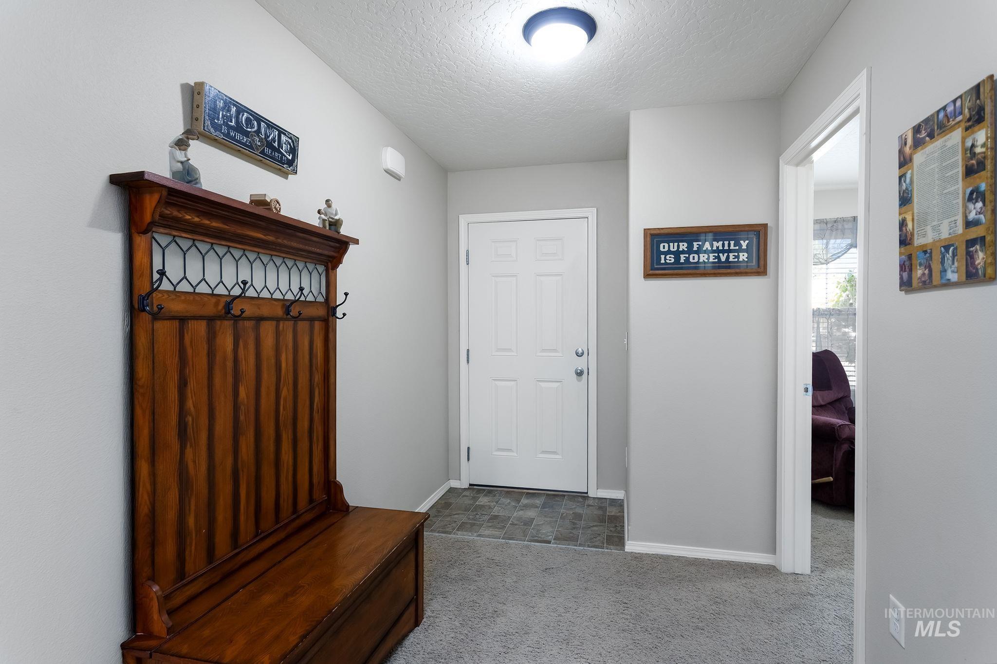 Mudroom featuring carpet flooring and a textured ceiling