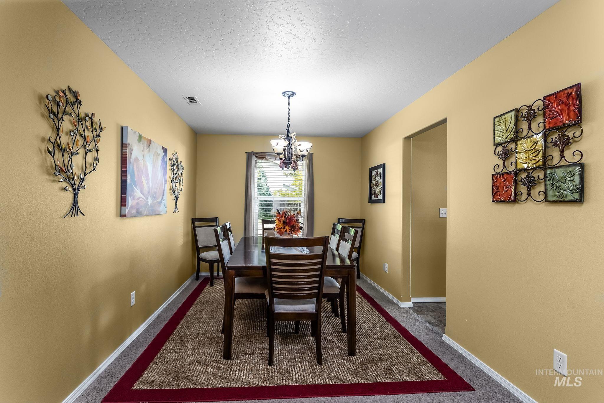 Dining room featuring a chandelier, a textured ceiling, and dark colored carpet
