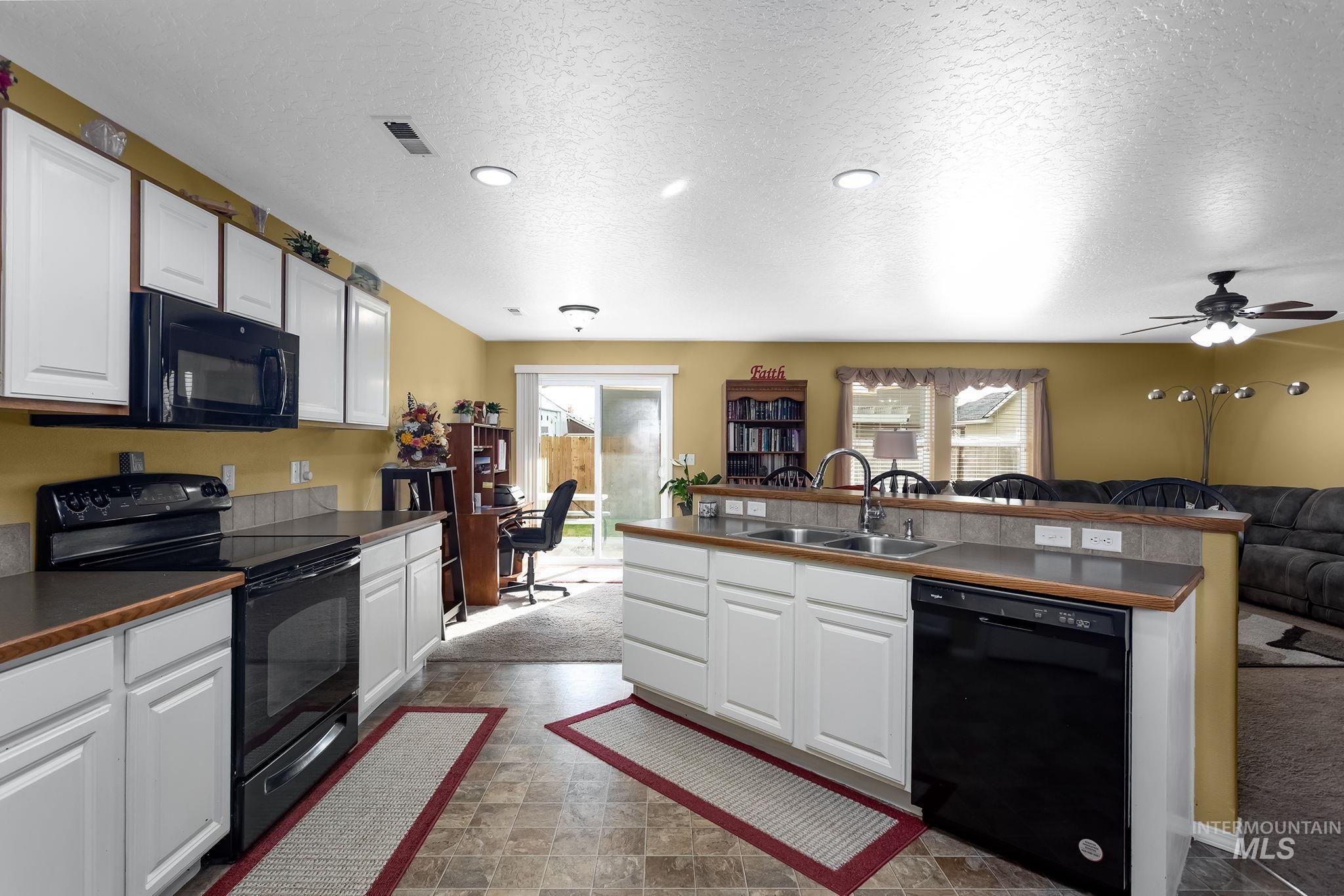 Kitchen featuring black appliances, white cabinetry, a textured ceiling, dark countertops, and open floor plan