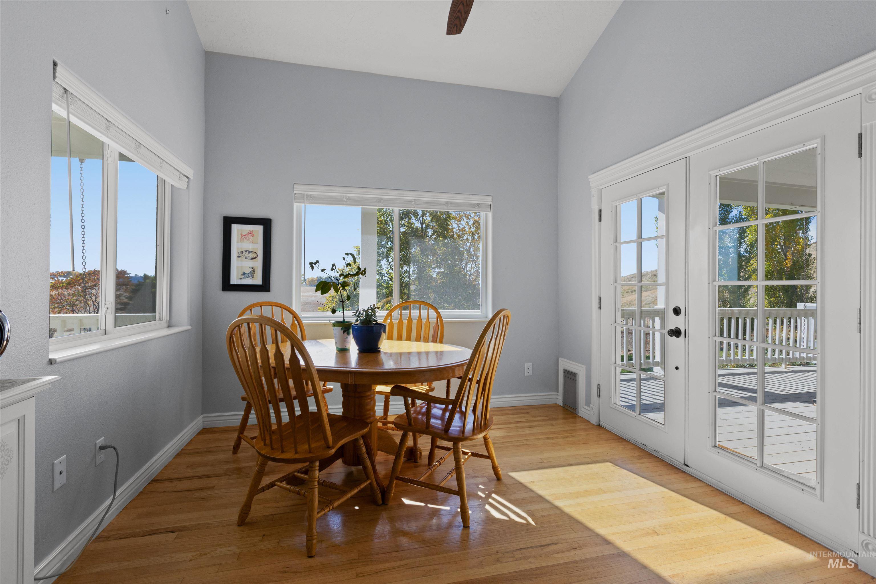 Dining space with light wood-style flooring, ceiling fan, and french doors