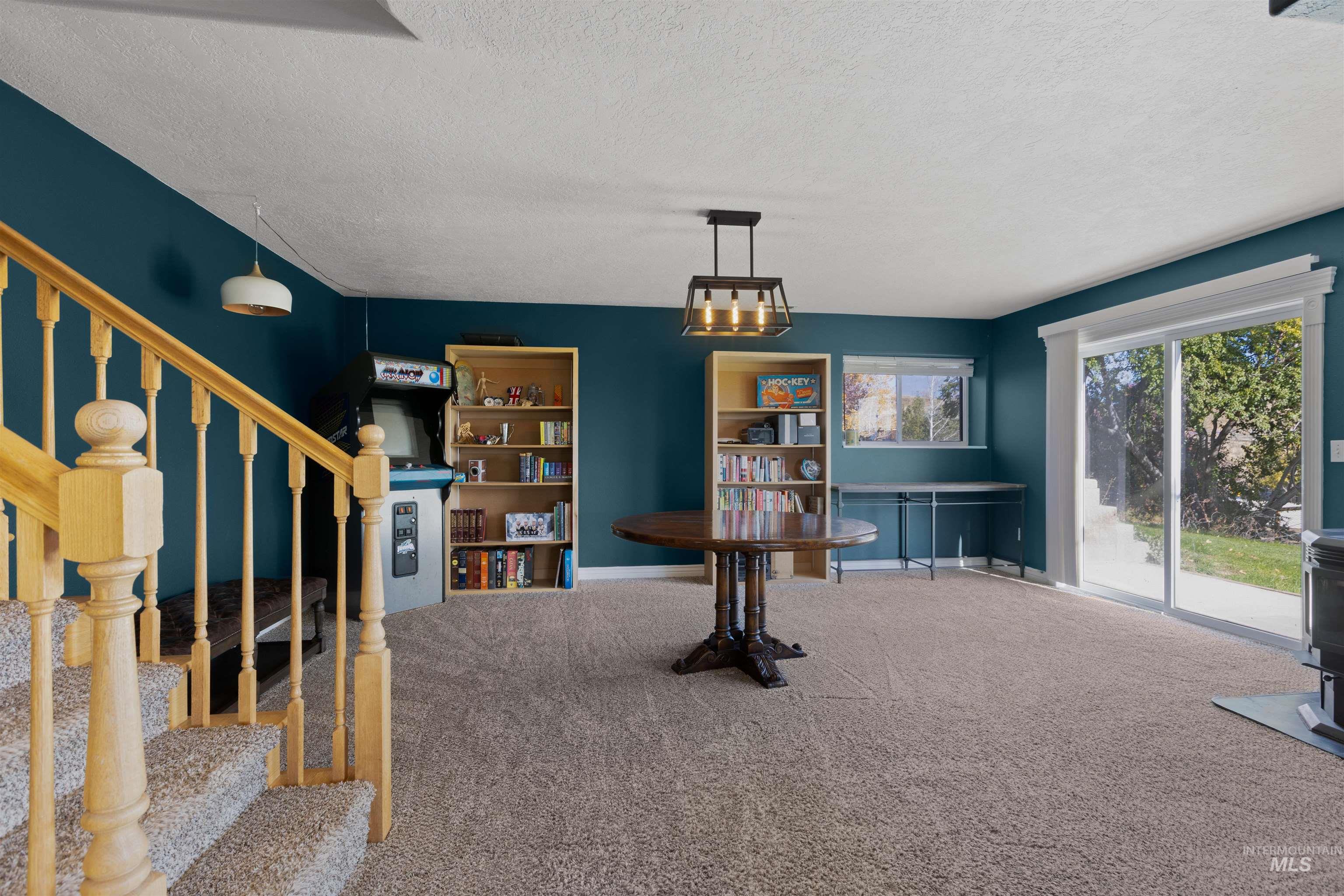 Carpeted dining area featuring a textured ceiling, stairway, and a wood stove