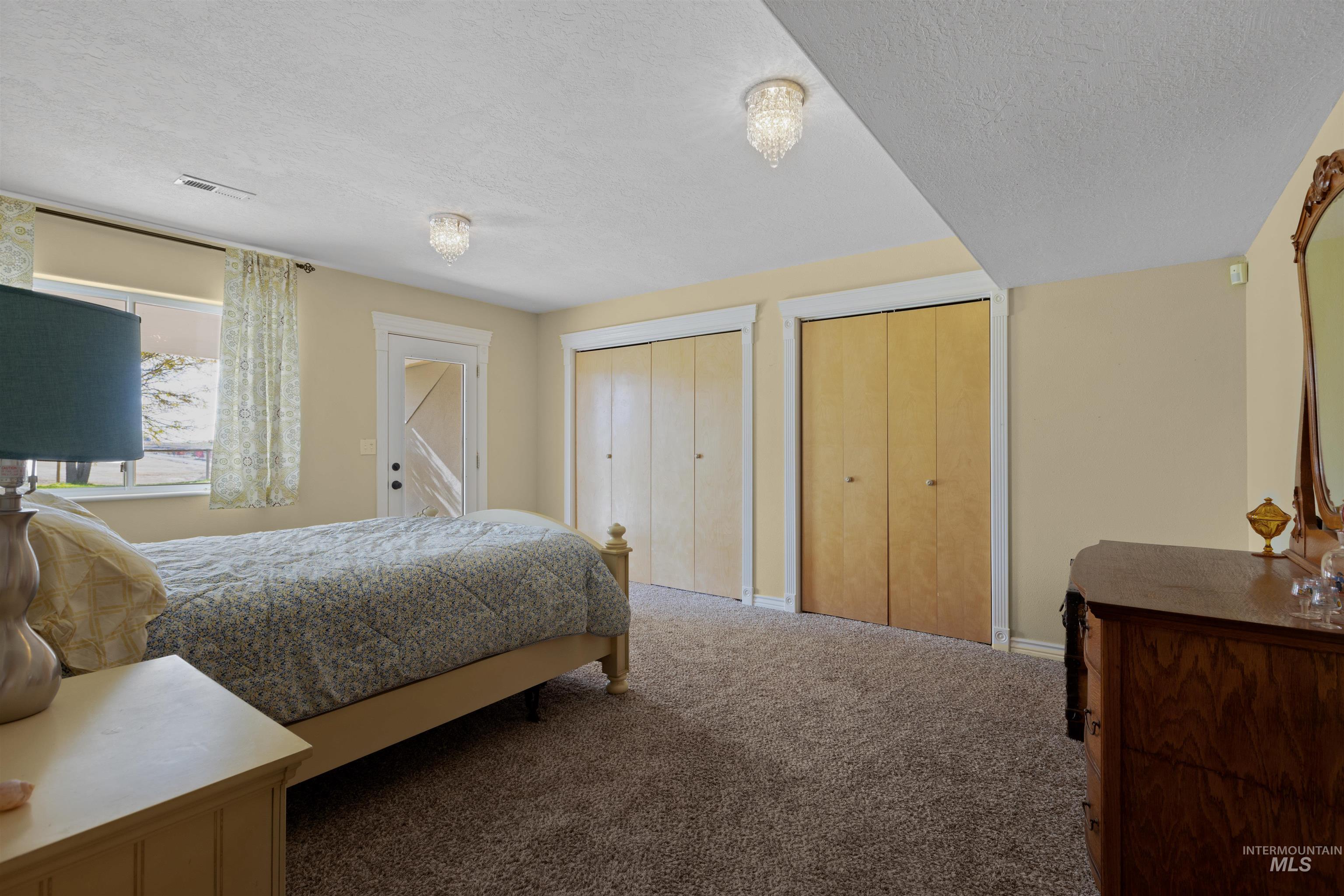 Bedroom featuring two closets, carpet floors, and a textured ceiling