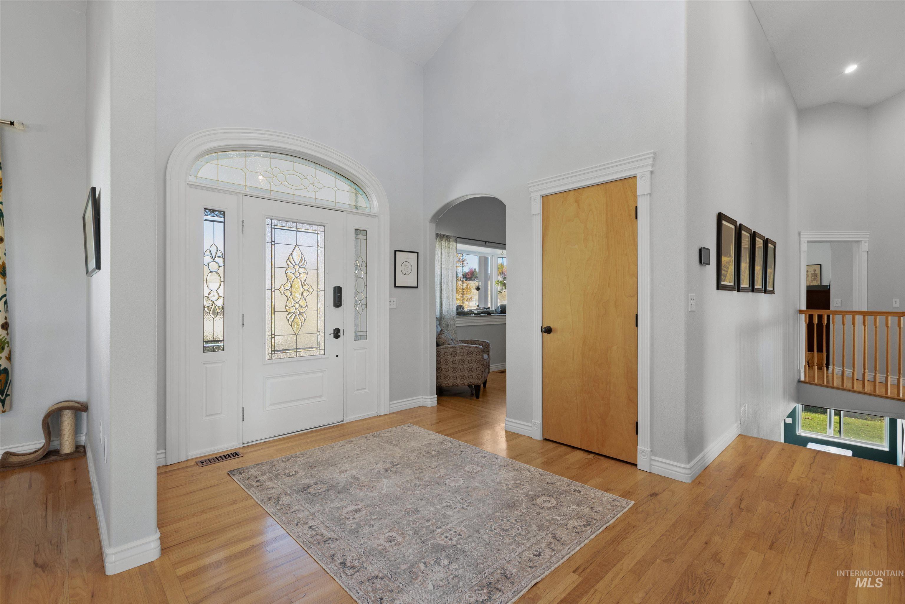 Entryway featuring a high ceiling, arched walkways, and light wood-type flooring