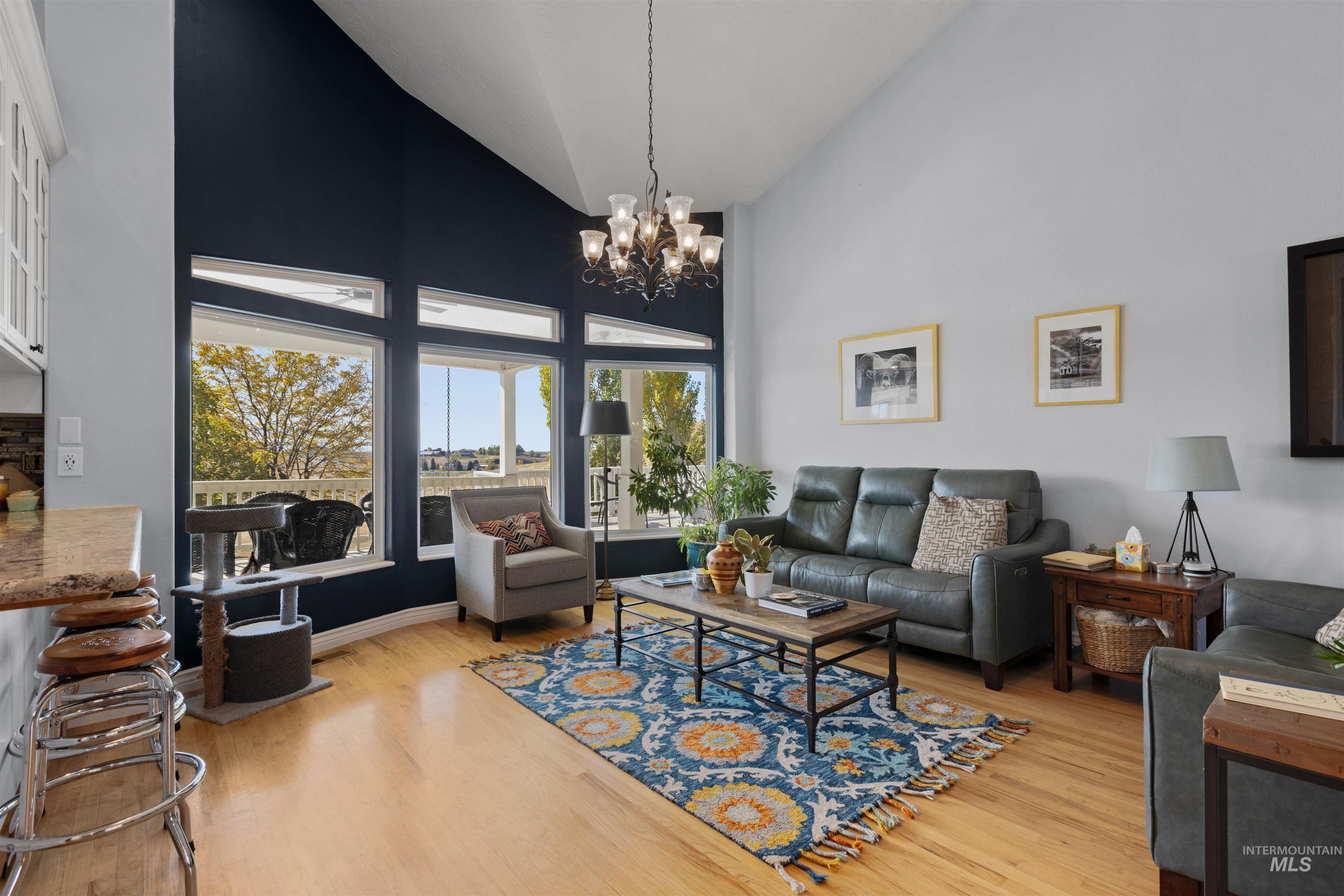 Living room with high vaulted ceiling, light wood finished floors, and a chandelier
