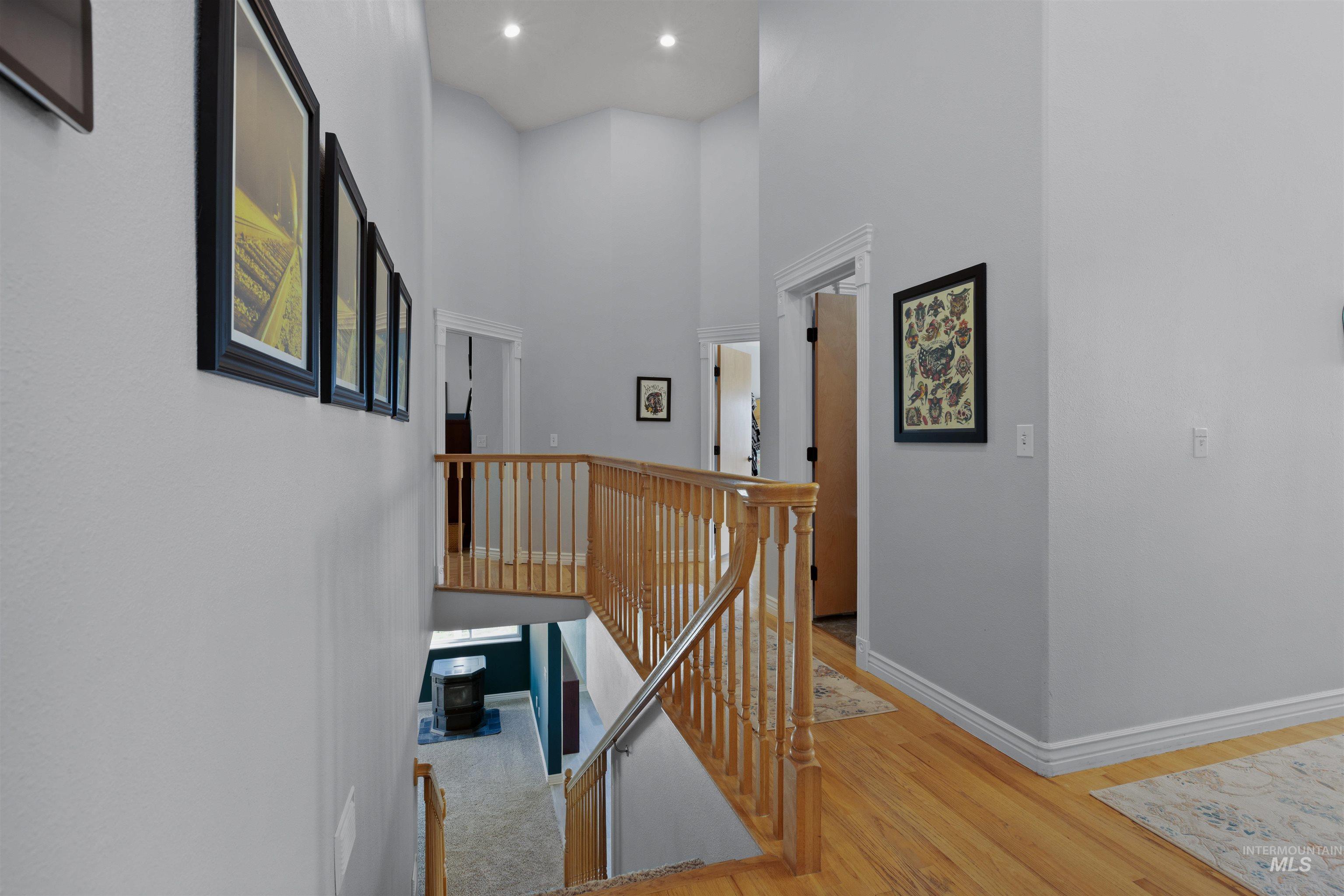 Corridor featuring an upstairs landing, light wood finished floors, and a towering ceiling