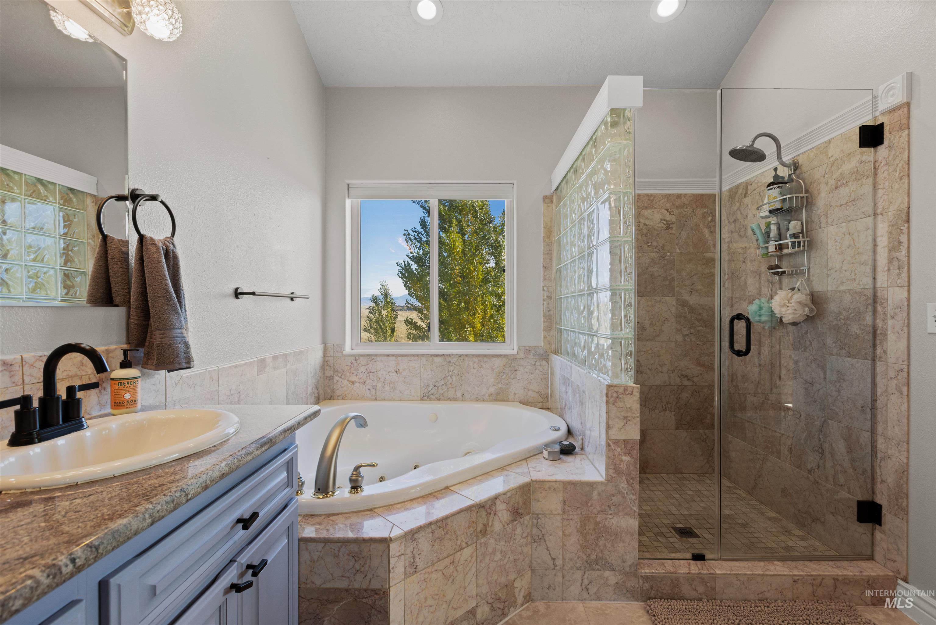 Bathroom with a tub with jets, vanity, a stall shower, and recessed lighting