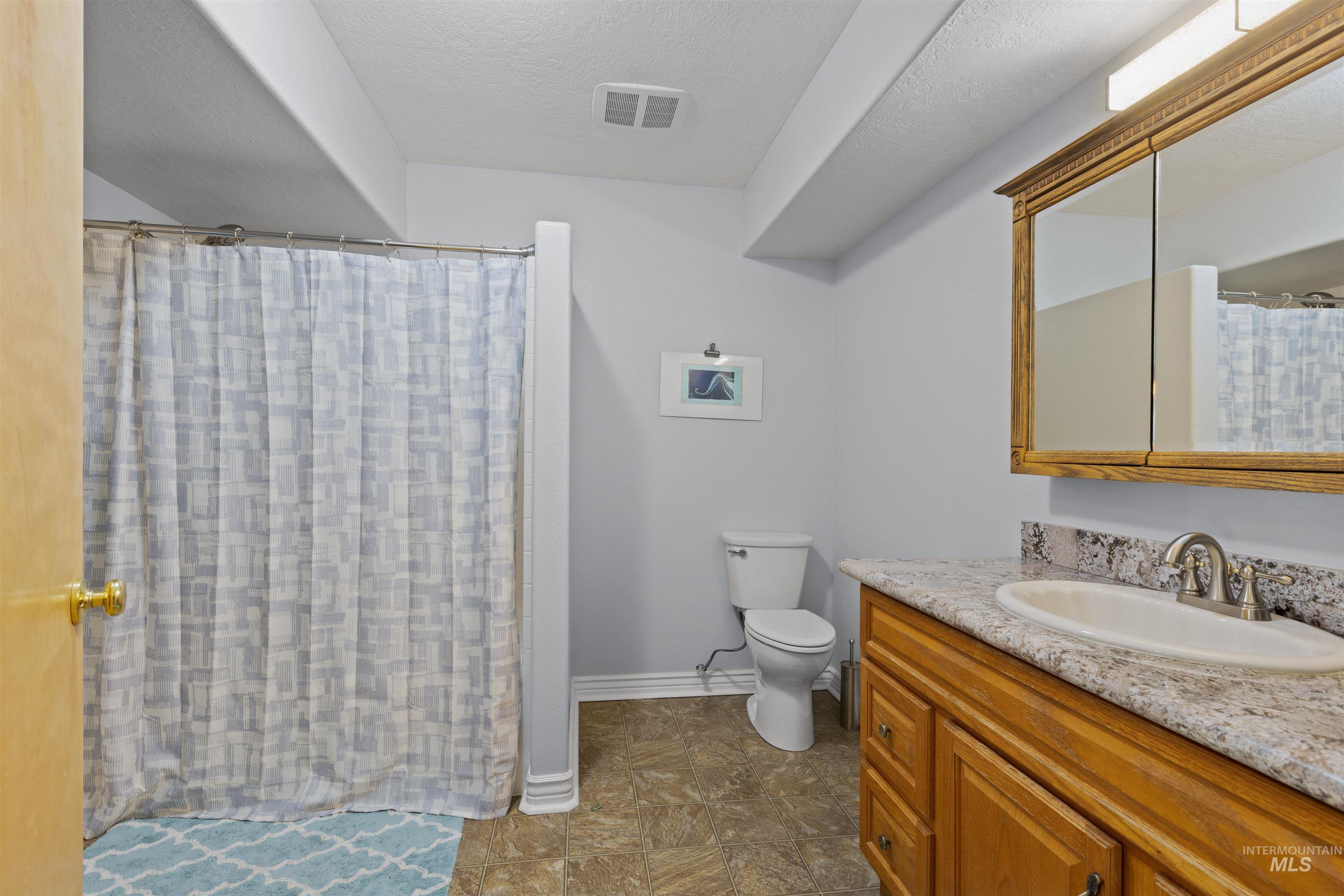 Full bath featuring curtained shower, vanity, and a textured ceiling