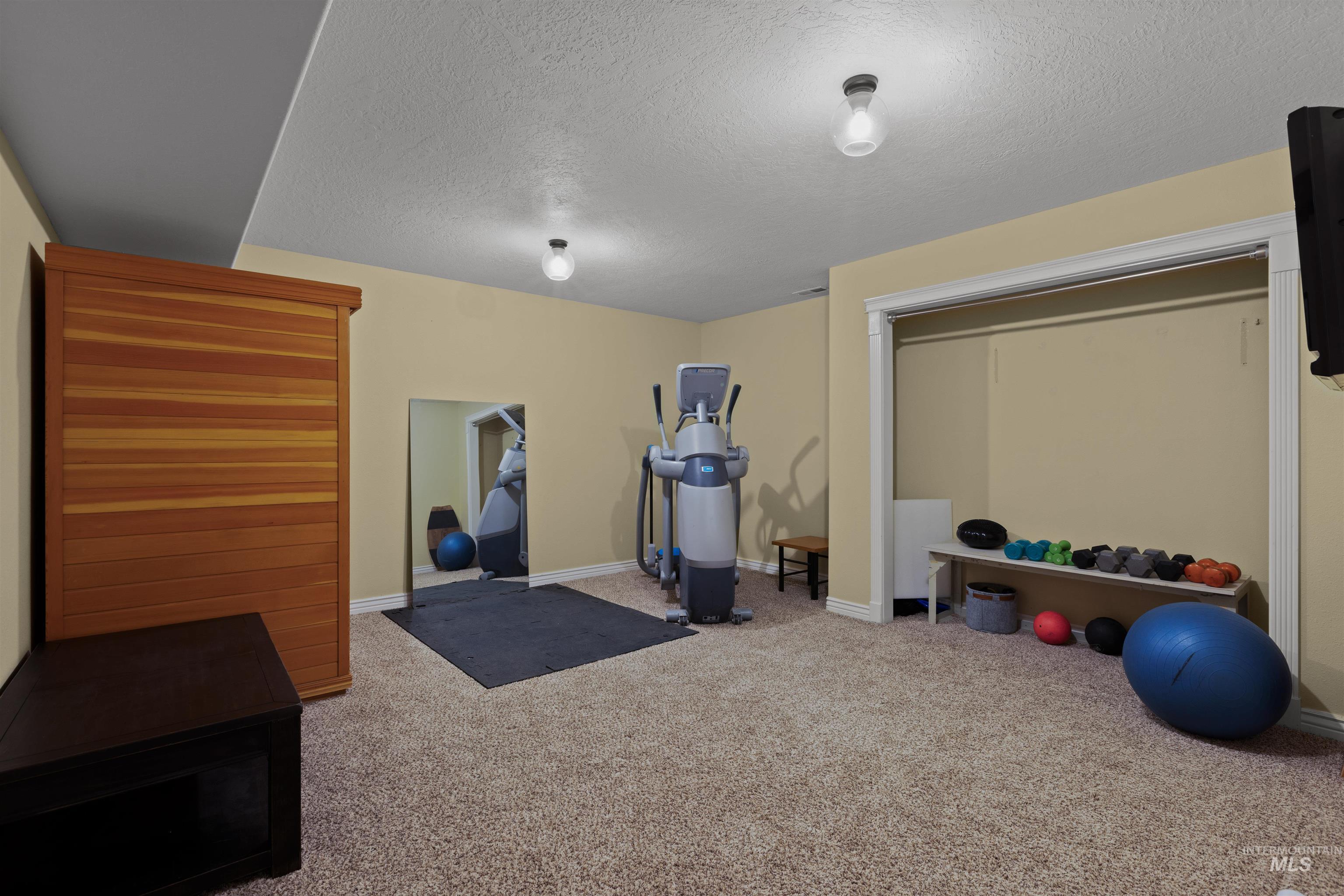 Exercise room with a textured ceiling and light carpet