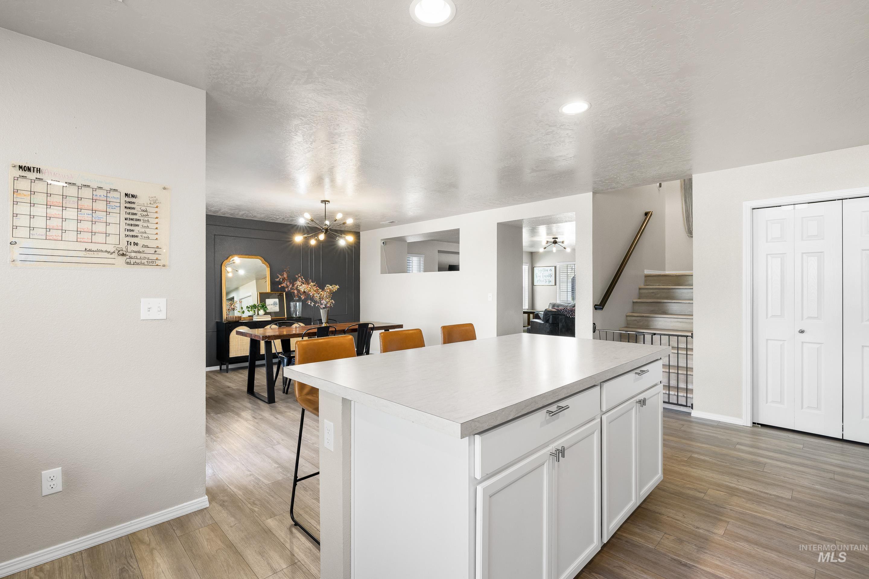Kitchen featuring a kitchen breakfast bar, white cabinets, light countertops, light wood-type flooring, and a kitchen island