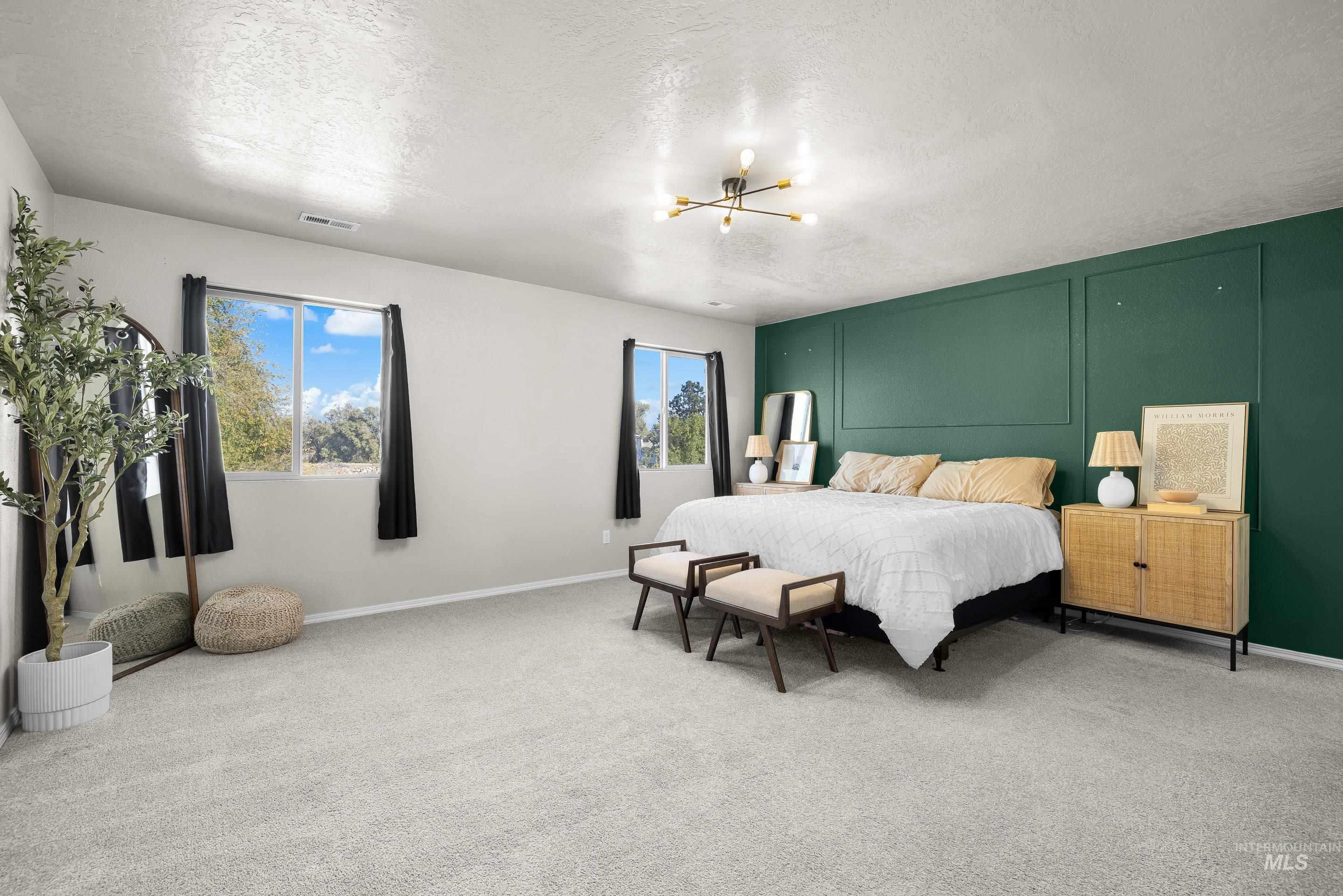 Bedroom featuring light colored carpet, a textured ceiling, and a chandelier