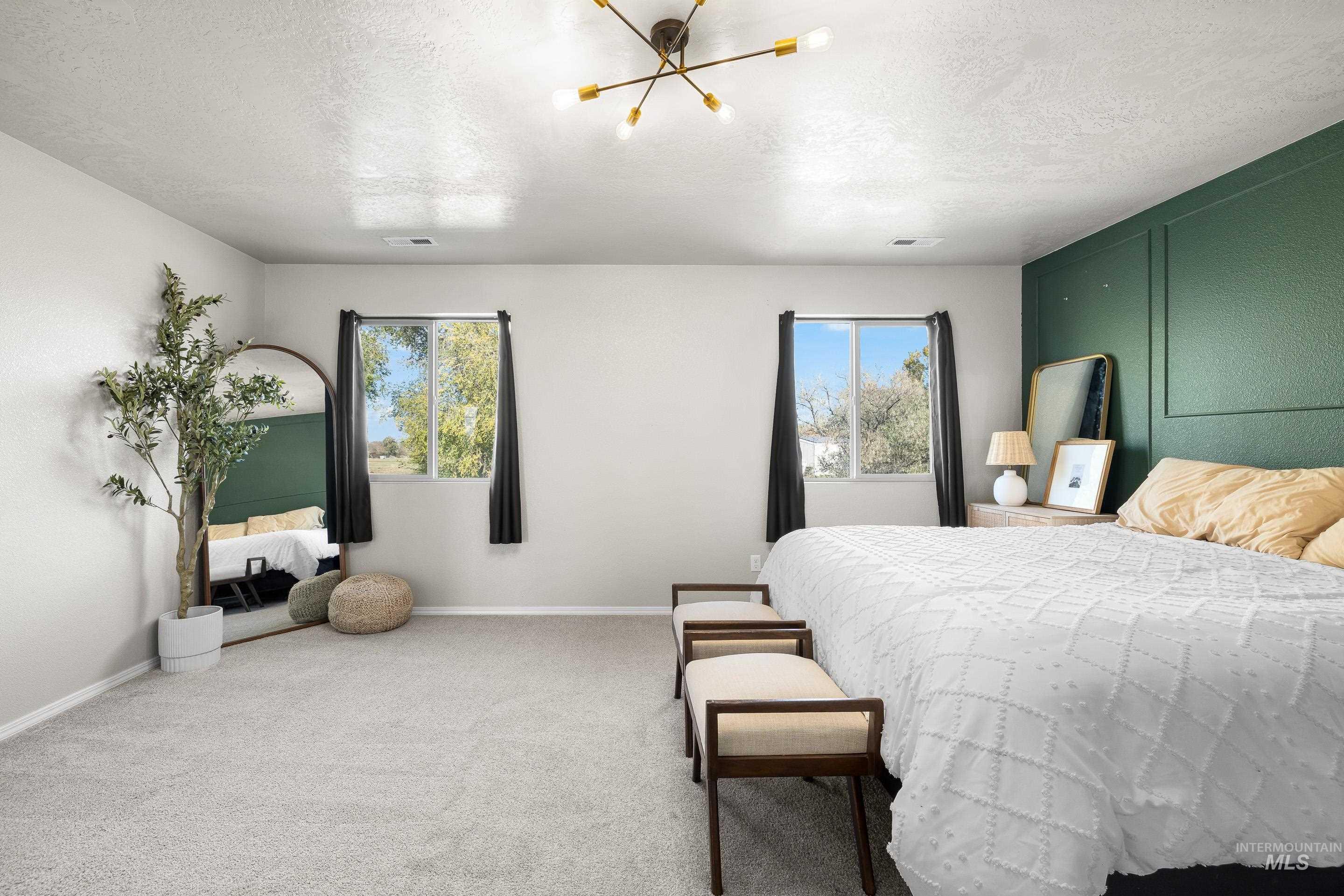 Carpeted bedroom with multiple windows, a chandelier, and a textured ceiling