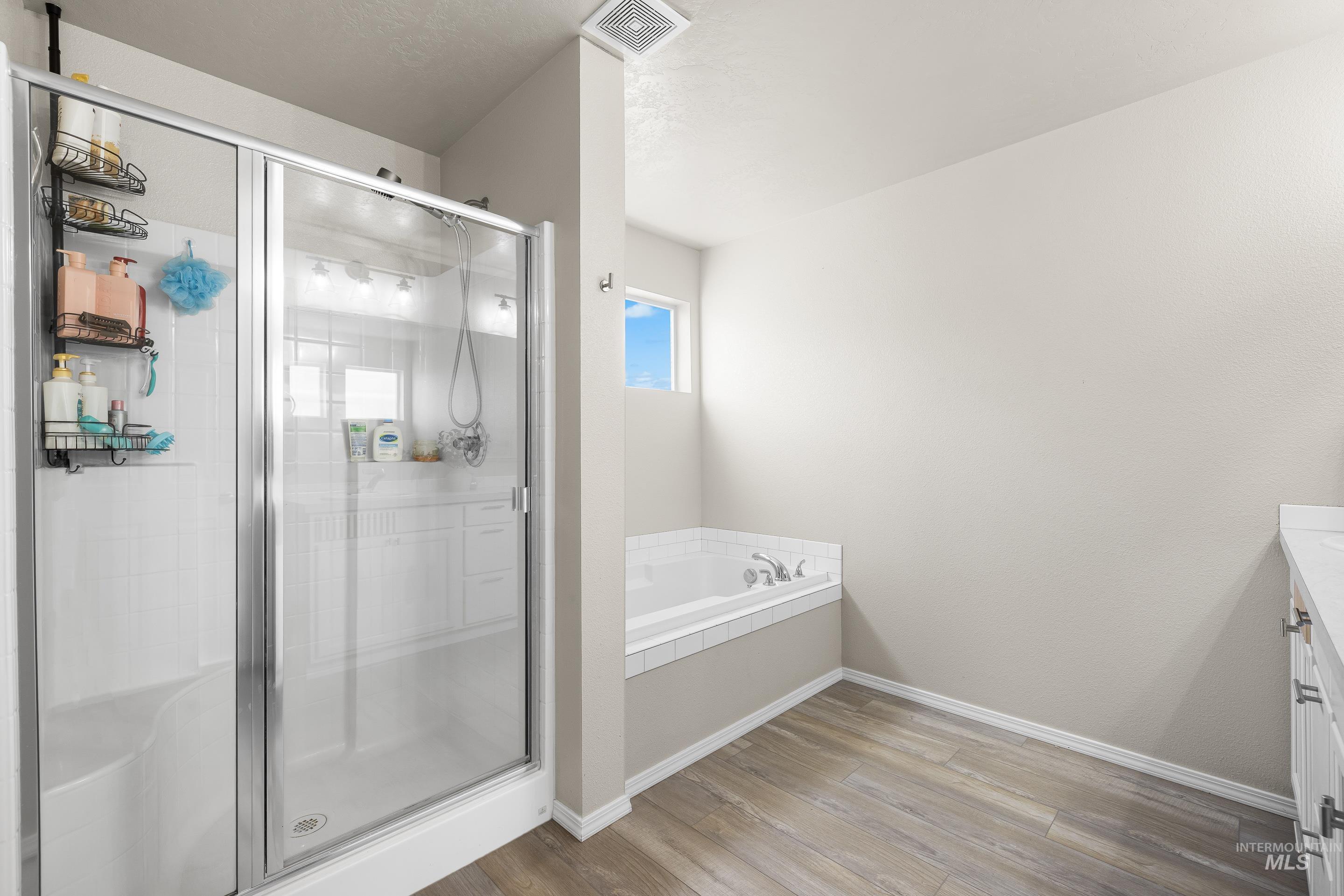 Full bathroom with vanity, light wood finished floors, a bath, and a stall shower