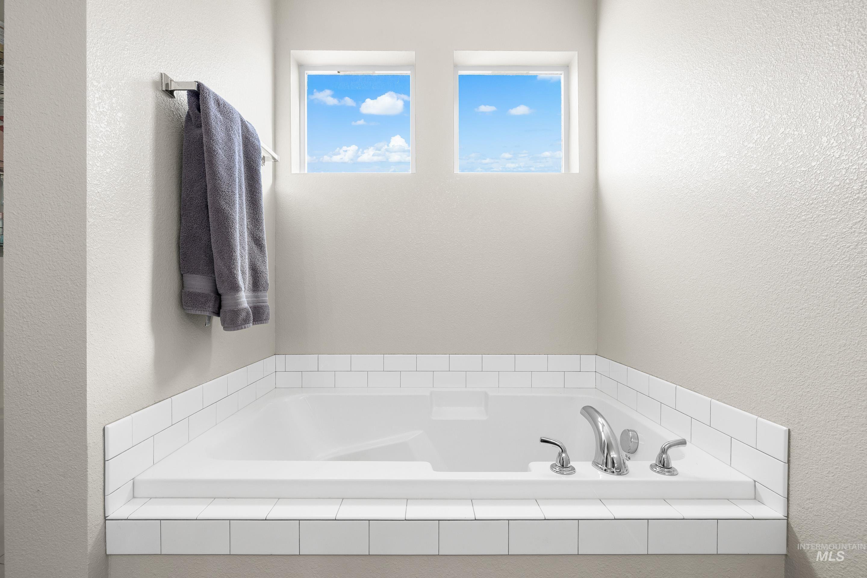 Bathroom featuring a textured wall and a garden tub