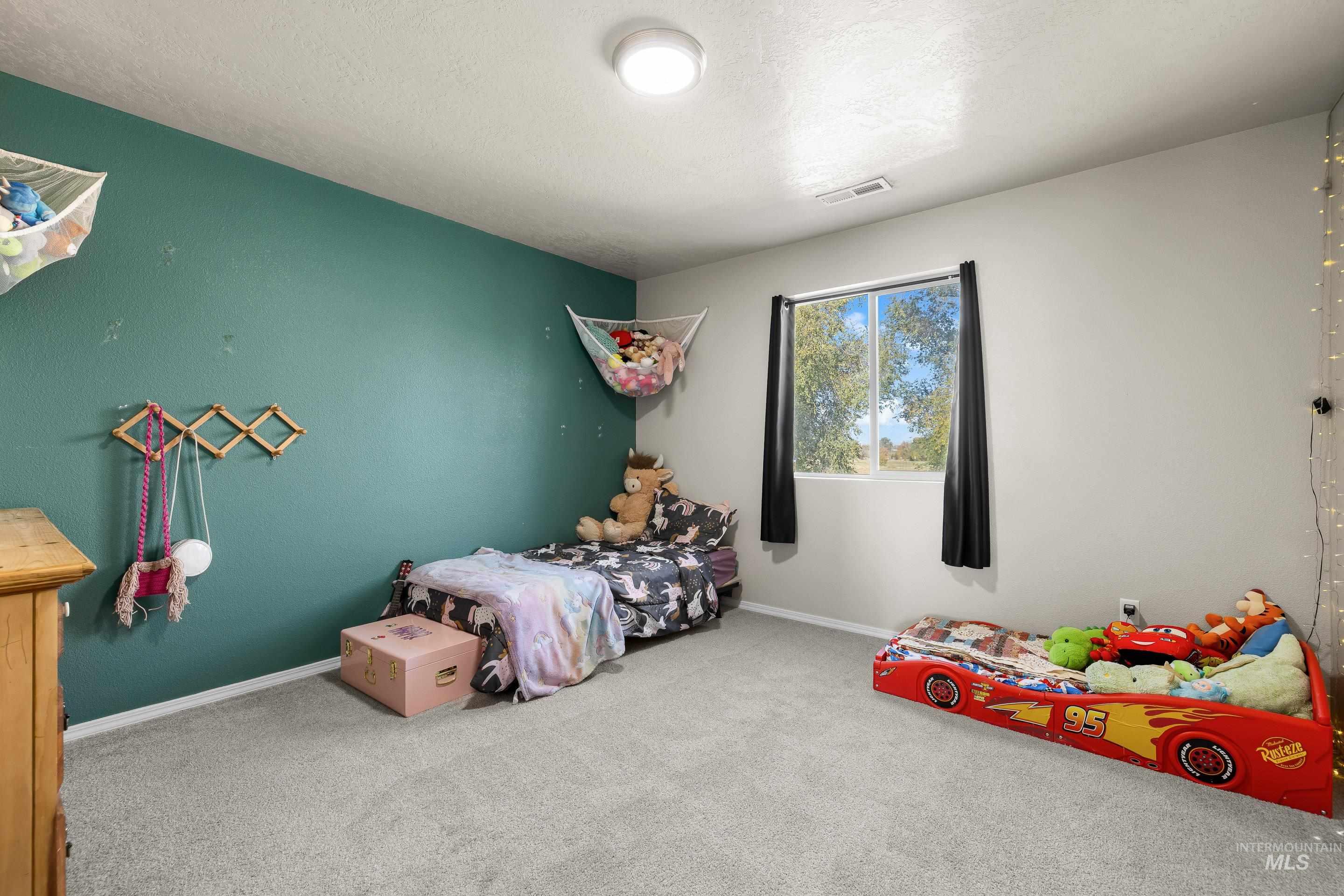 Carpeted bedroom featuring baseboards and a textured ceiling