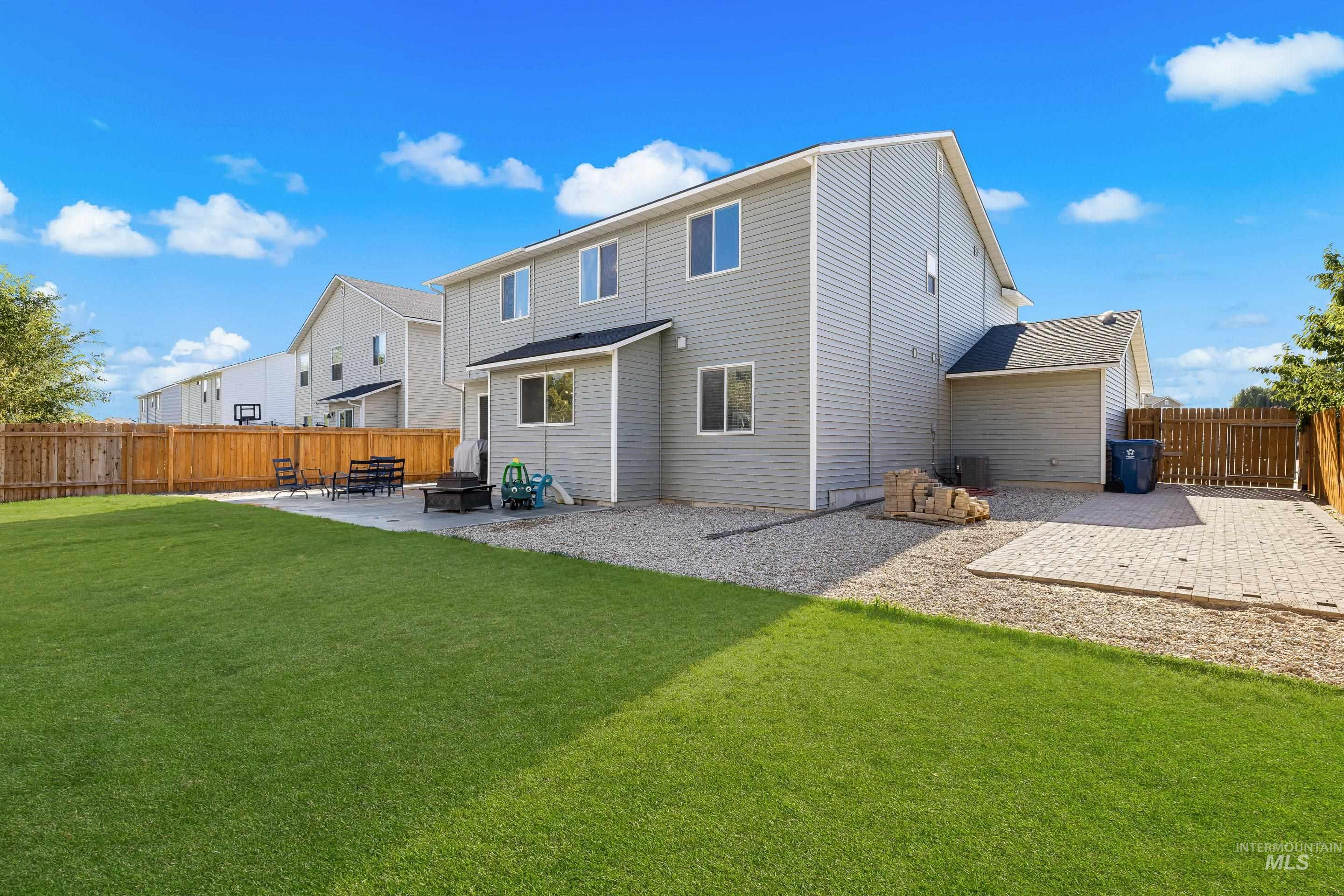 Rear view of house with a fenced backyard and a patio