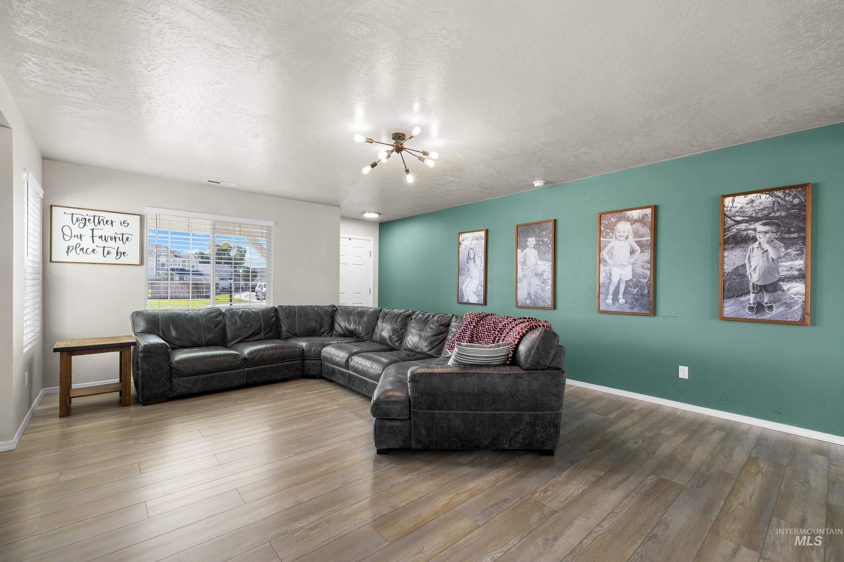 Living room featuring a textured ceiling, wood finished floors, and a chandelier