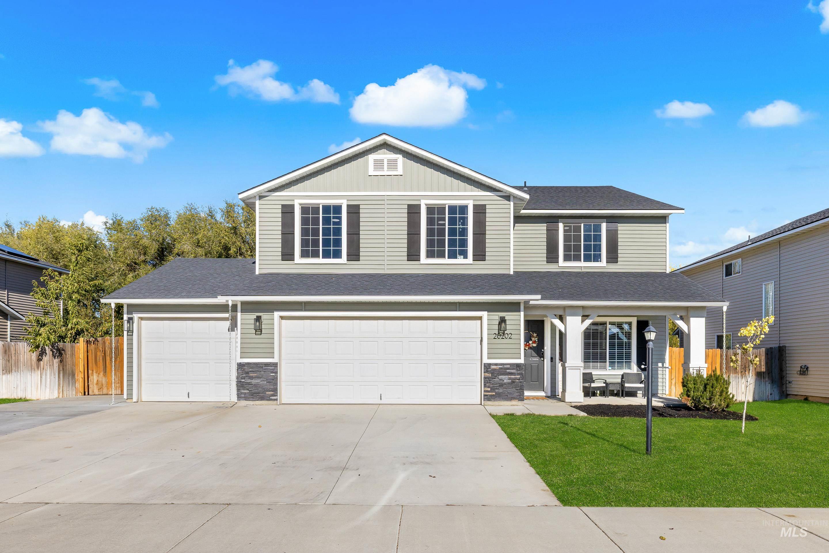 View of front of house with covered porch, driveway, an attached garage, a shingled roof, and stone siding