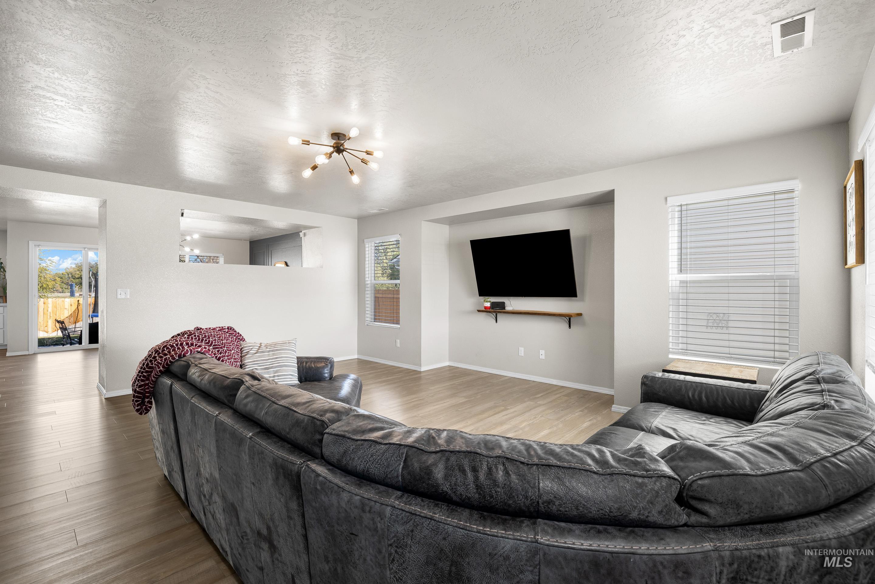 Living room featuring a textured ceiling, wood finished floors, and a chandelier