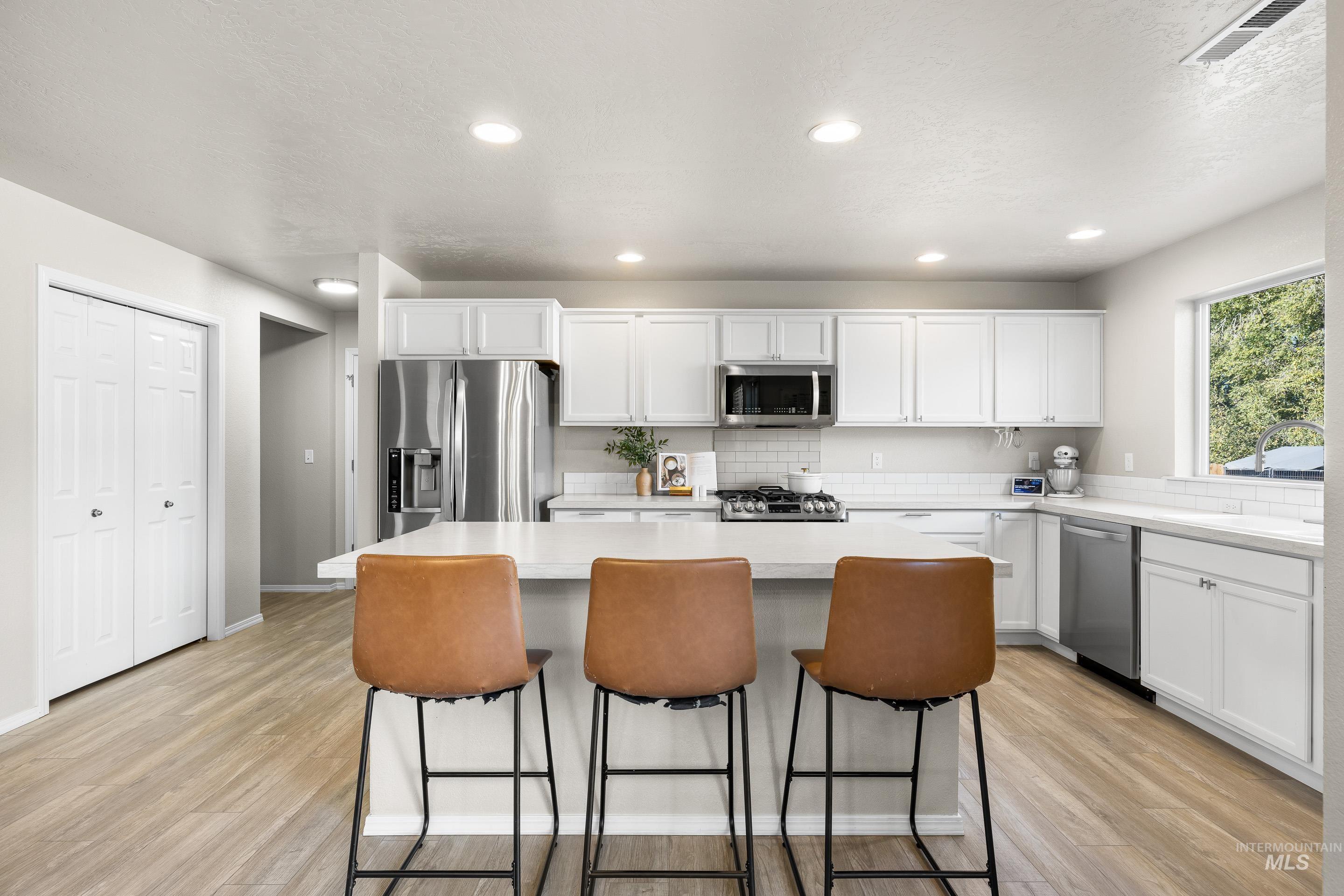 Kitchen featuring white cabinetry, a kitchen island, light wood-type flooring, and recessed lighting