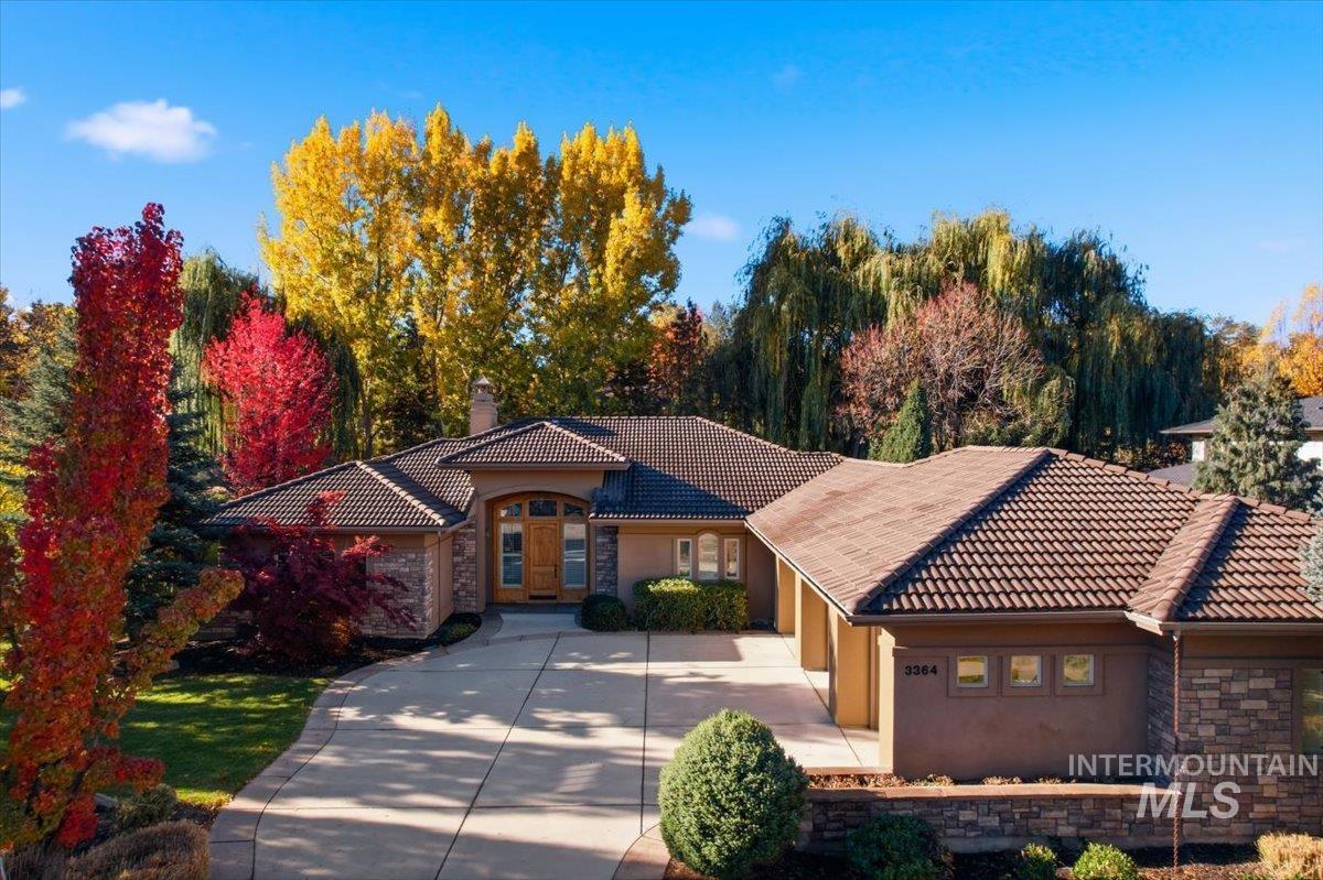 Mediterranean / spanish home with stone siding, a chimney, a tile roof, and stucco siding