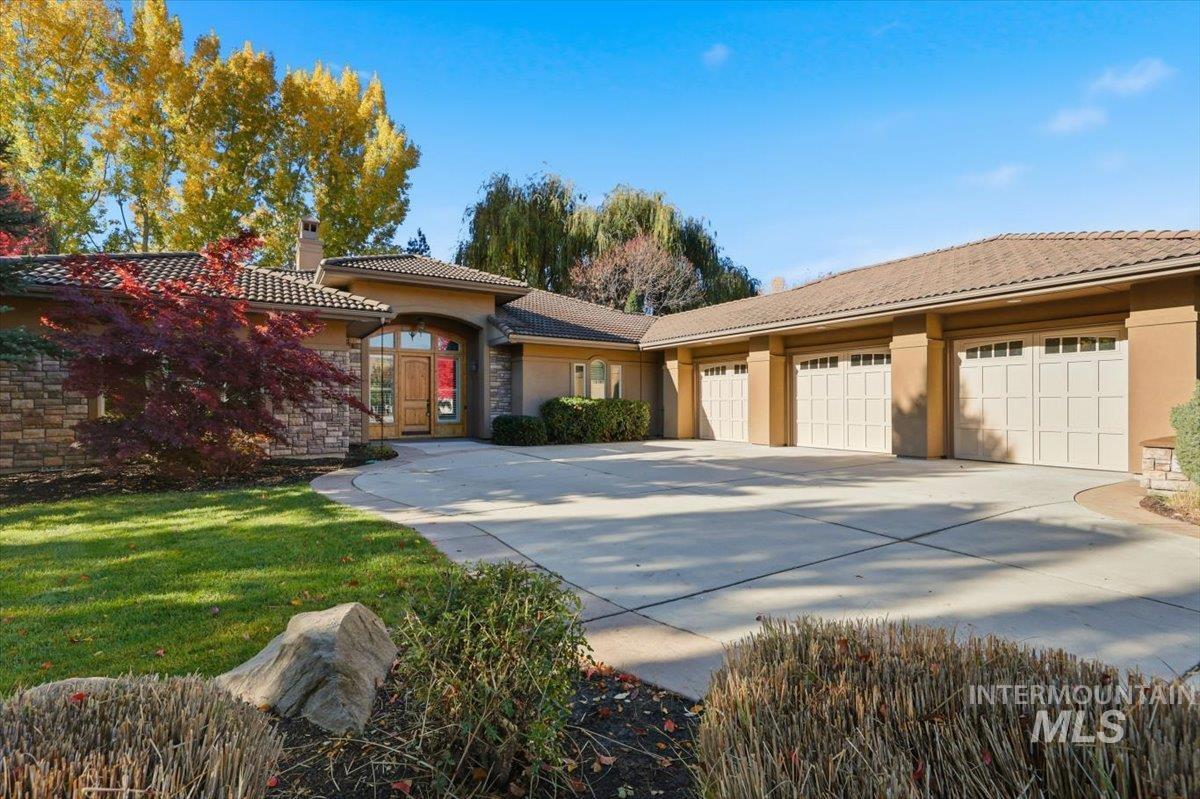 View of front of house with a chimney, stucco siding, driveway, a garage, and a tiled roof