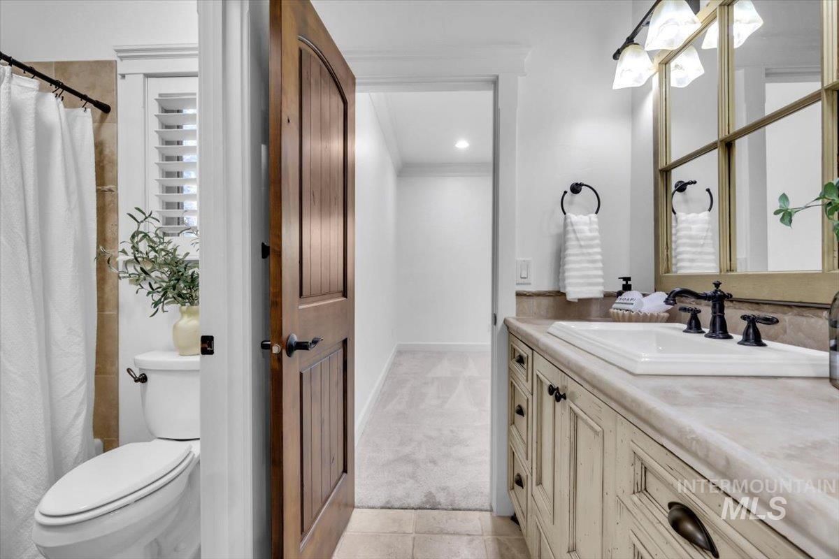 Full bath featuring vanity, a shower with shower curtain, light tile patterned flooring, light carpet, and crown molding