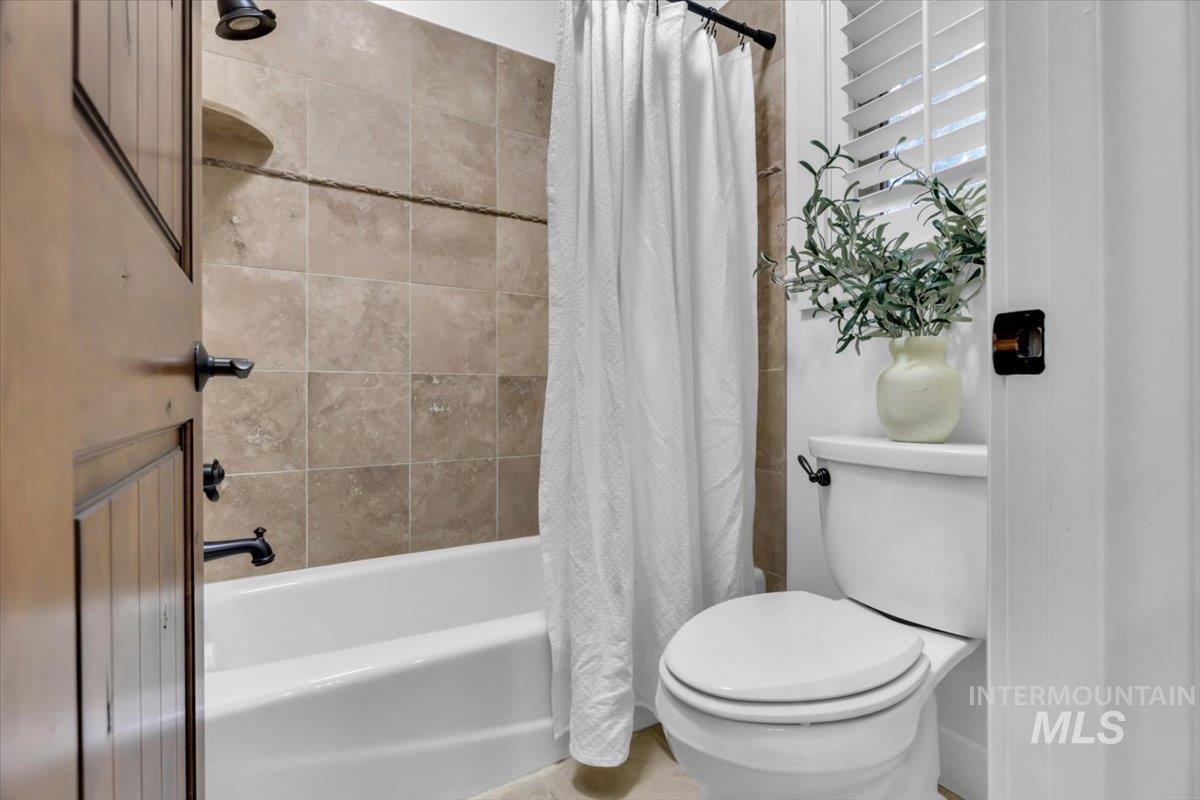 Bathroom with shower / bathtub combination with curtain and toilet