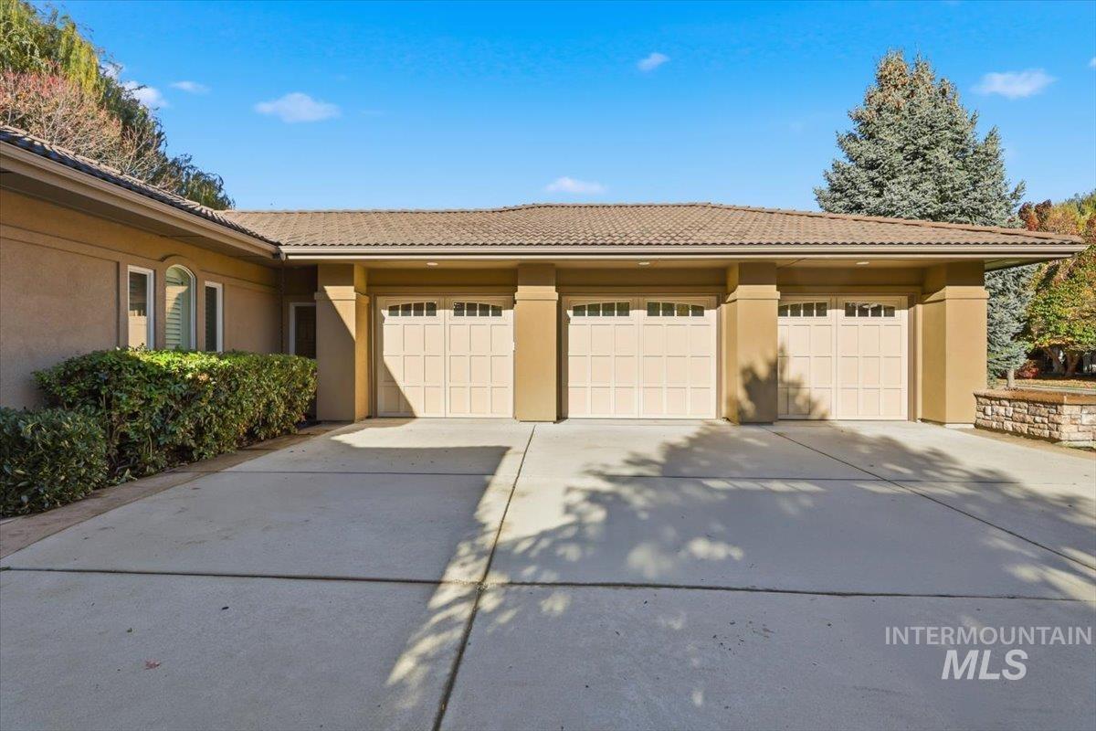 View of front facade featuring stucco siding, driveway, a tile roof, and an attached garage