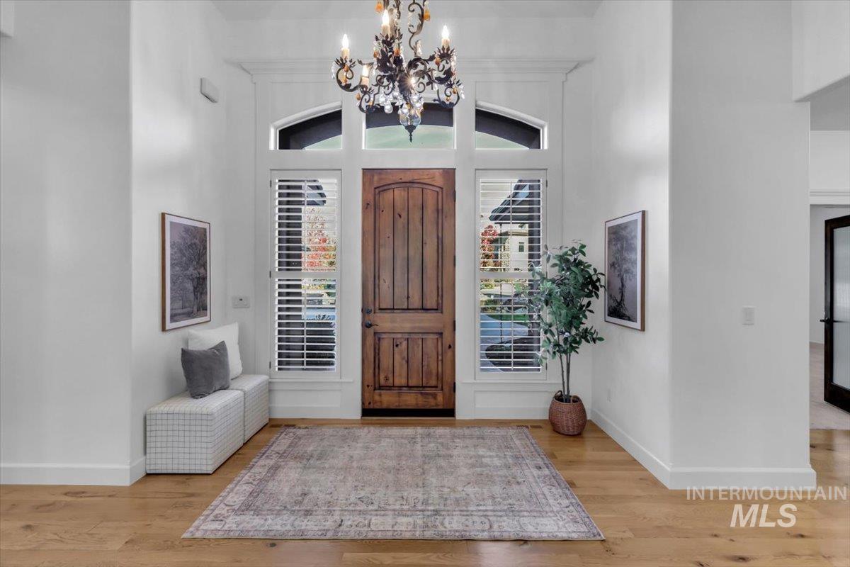 Foyer featuring light wood-style flooring, a chandelier, and a high ceiling
