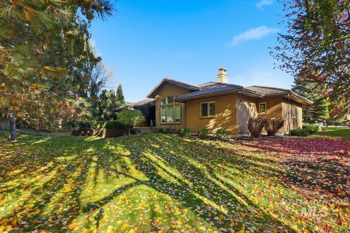 View of property exterior with a chimney, a tile roof, and a lawn