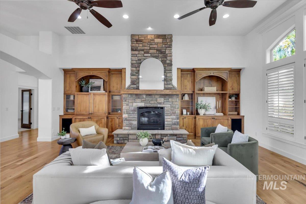 Living room with ceiling fan, light wood-style floors, a fireplace, and recessed lighting