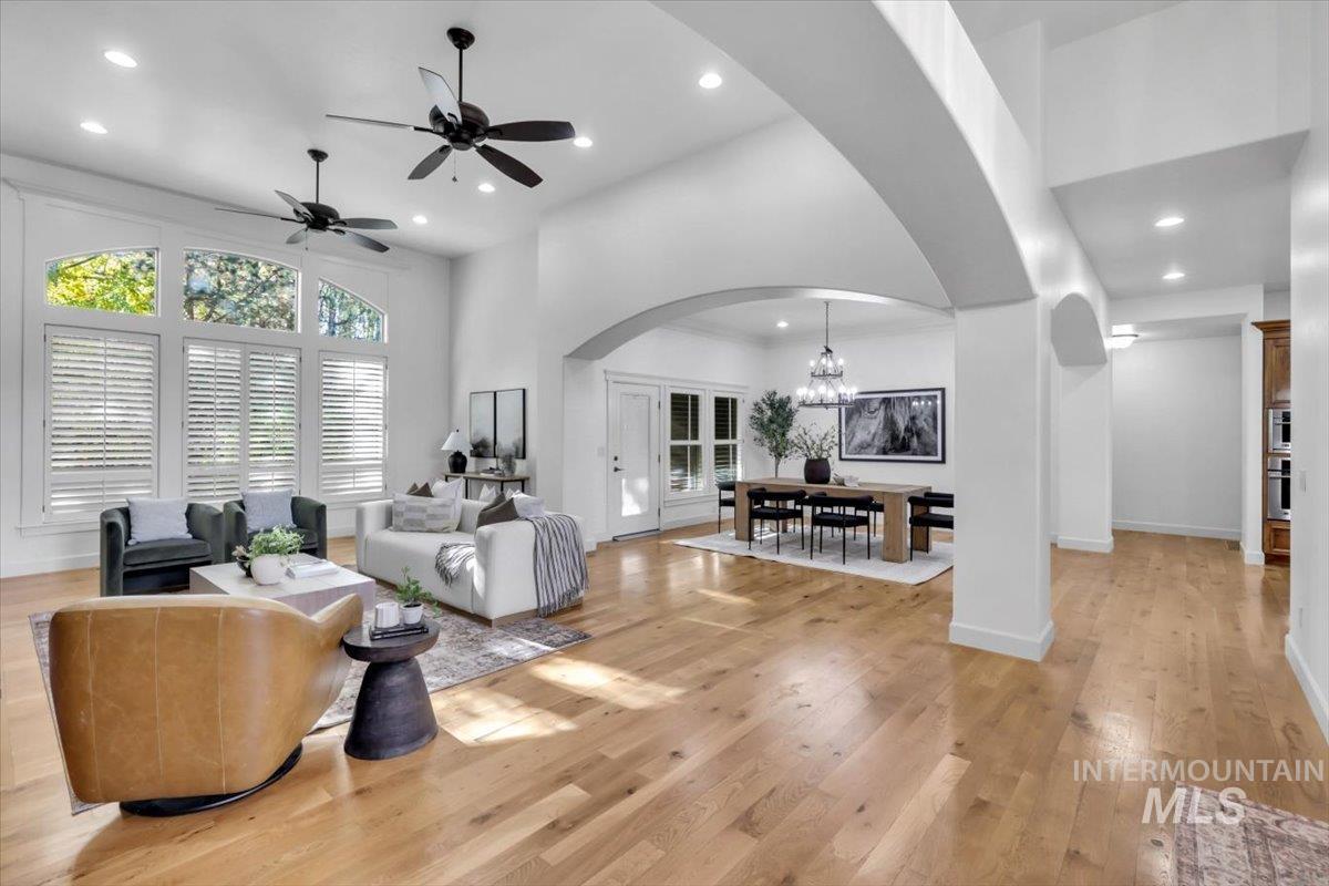 Living room featuring arched walkways, a chandelier, light wood-style flooring, plenty of natural light, and recessed lighting