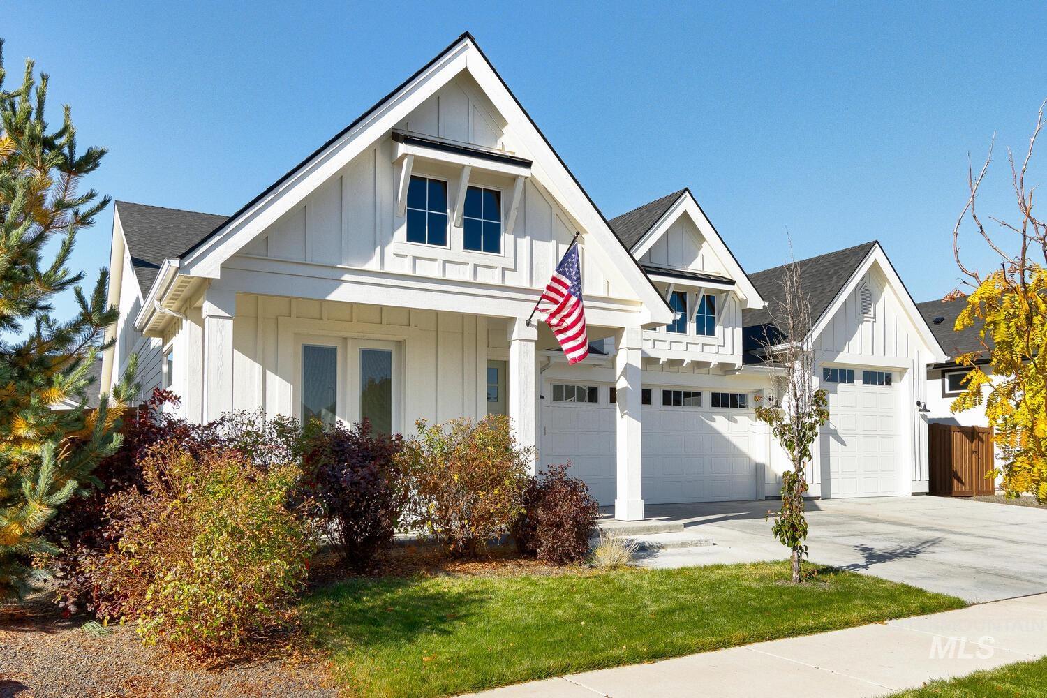 Modern farmhouse featuring board and batten siding, driveway, a shingled roof, and a front lawn