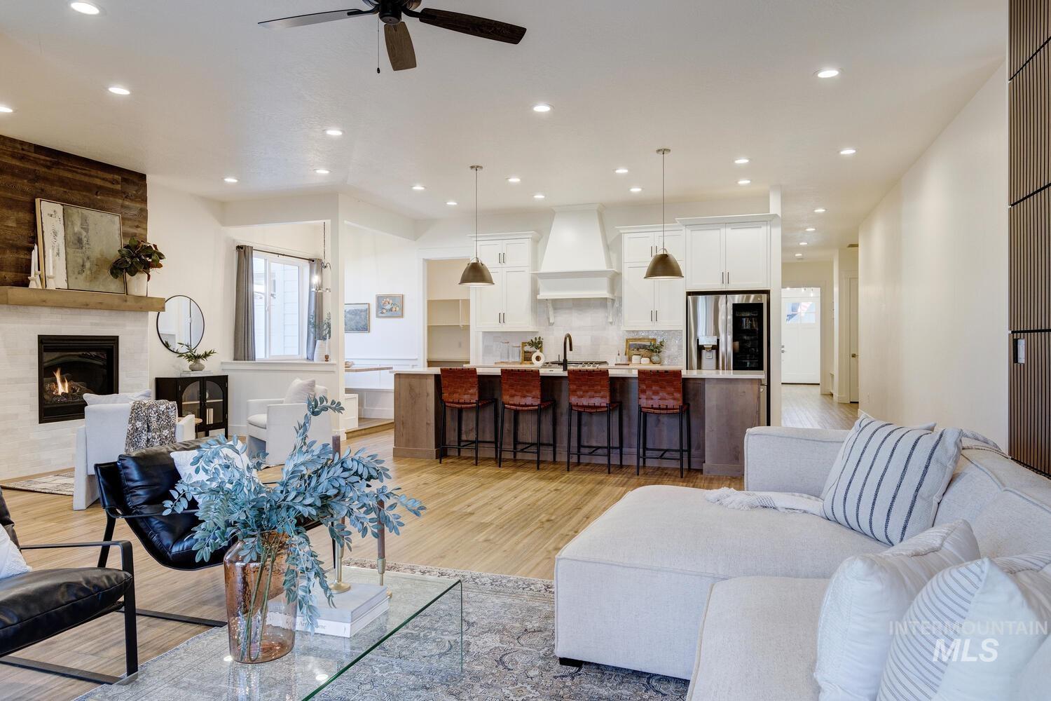 Living room with light wood finished floors, recessed lighting, a fireplace, and ceiling fan
