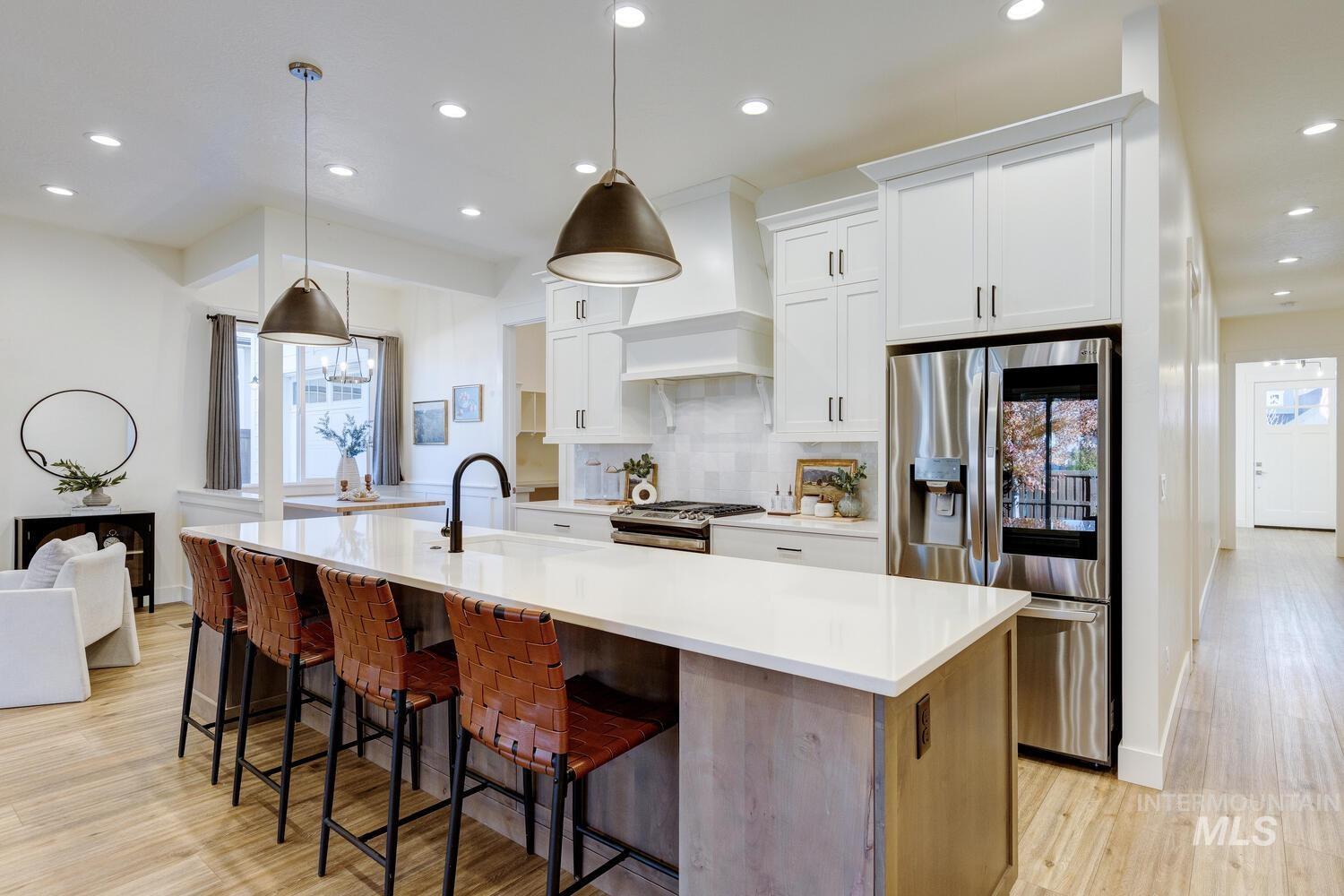 Kitchen featuring appliances with stainless steel finishes, white cabinets, decorative backsplash, recessed lighting, and a kitchen breakfast bar