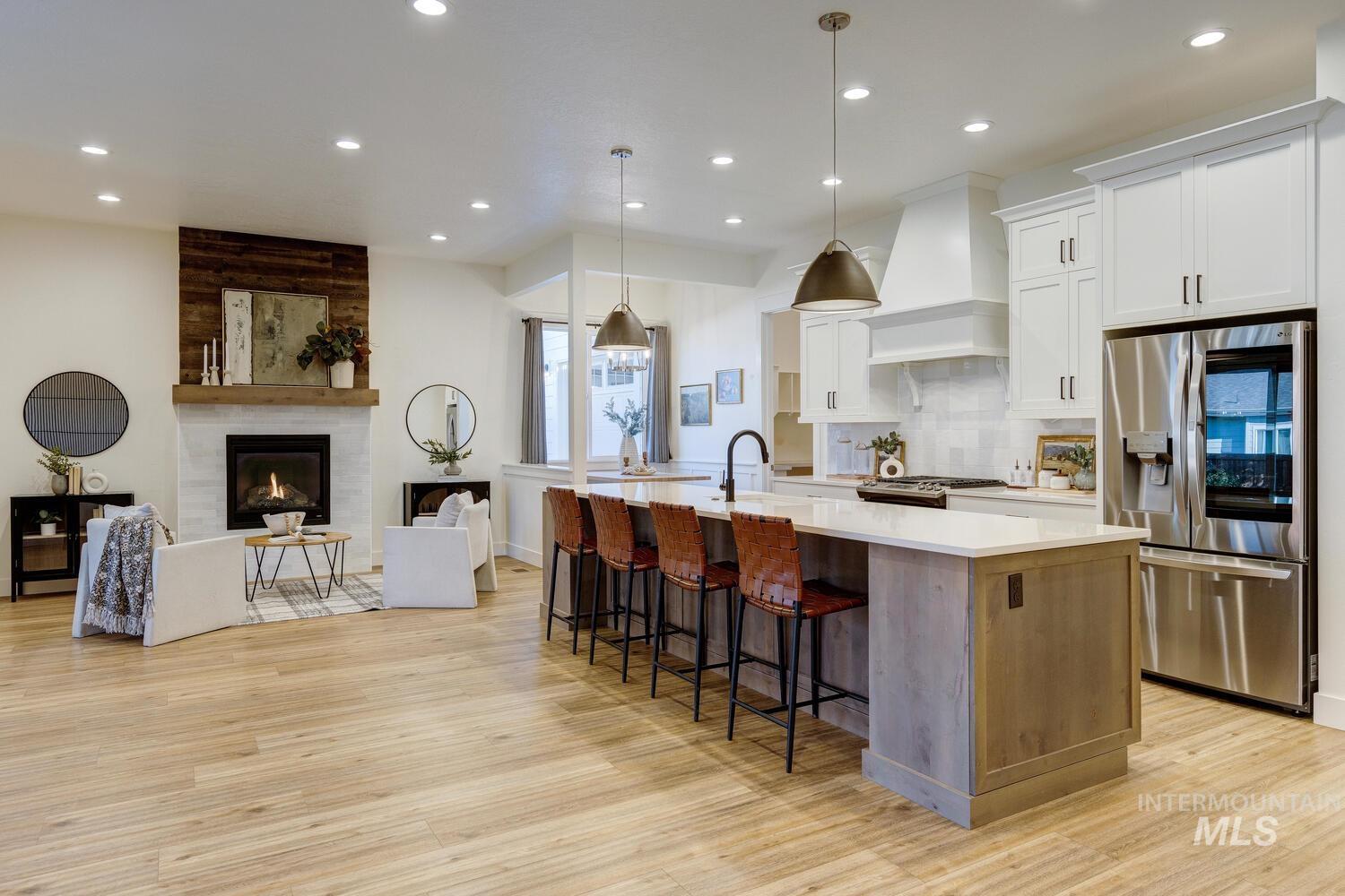 Kitchen featuring stainless steel appliances, white cabinetry, hanging light fixtures, open floor plan, and tasteful backsplash