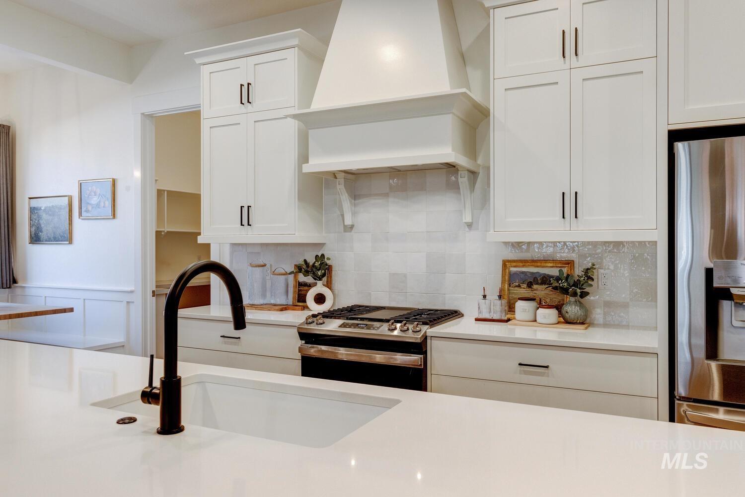 Kitchen with appliances with stainless steel finishes, tasteful backsplash, and white cabinetry