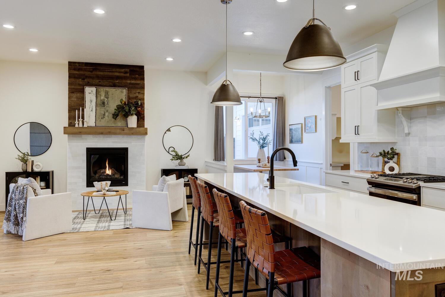 Kitchen with recessed lighting, white cabinetry, gas stove, an island with sink, and decorative light fixtures