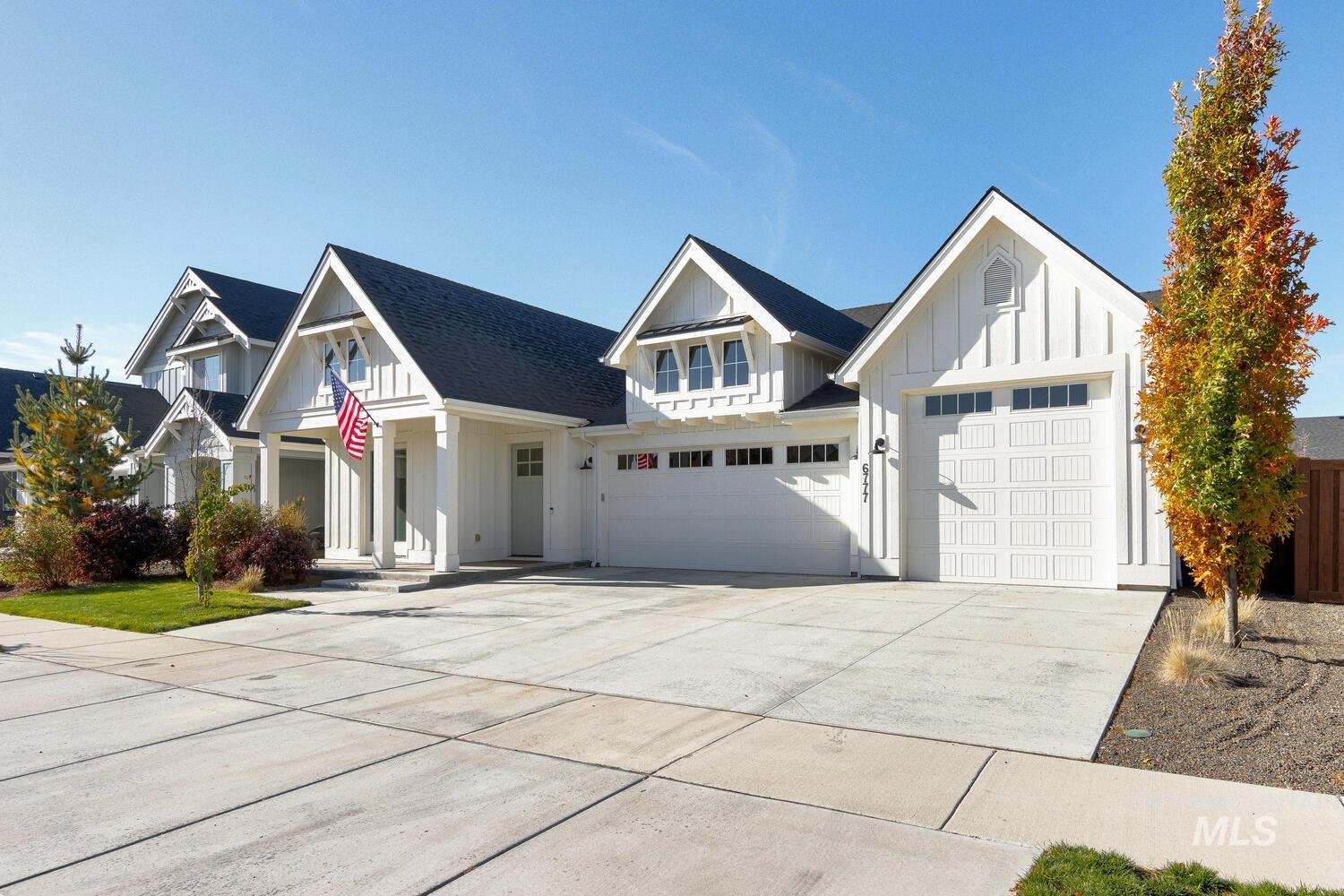 Modern inspired farmhouse with board and batten siding, driveway, an attached garage, and a shingled roof