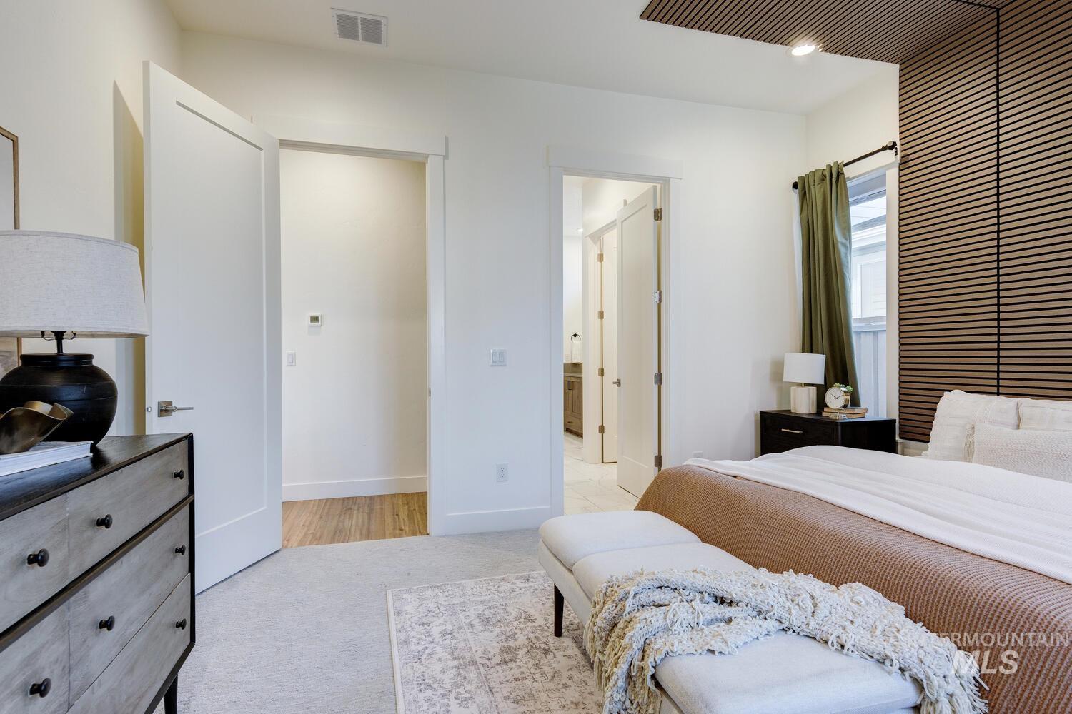 Bedroom featuring light colored carpet and connected bathroom