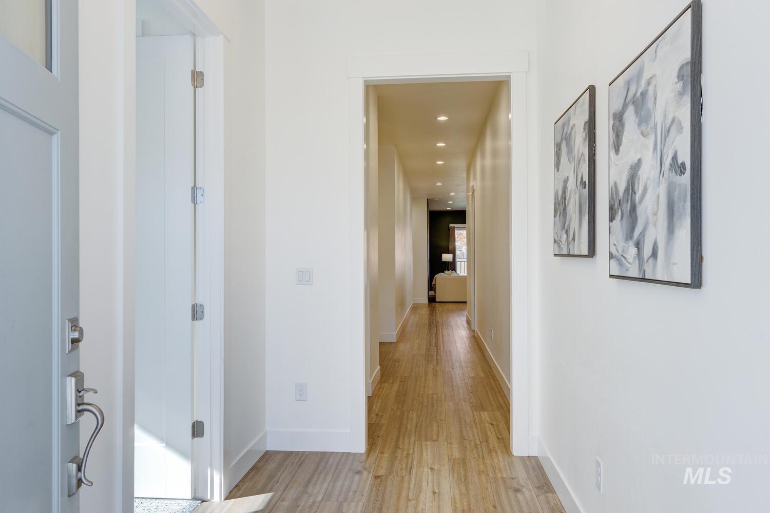 Hallway with light wood-style flooring and recessed lighting