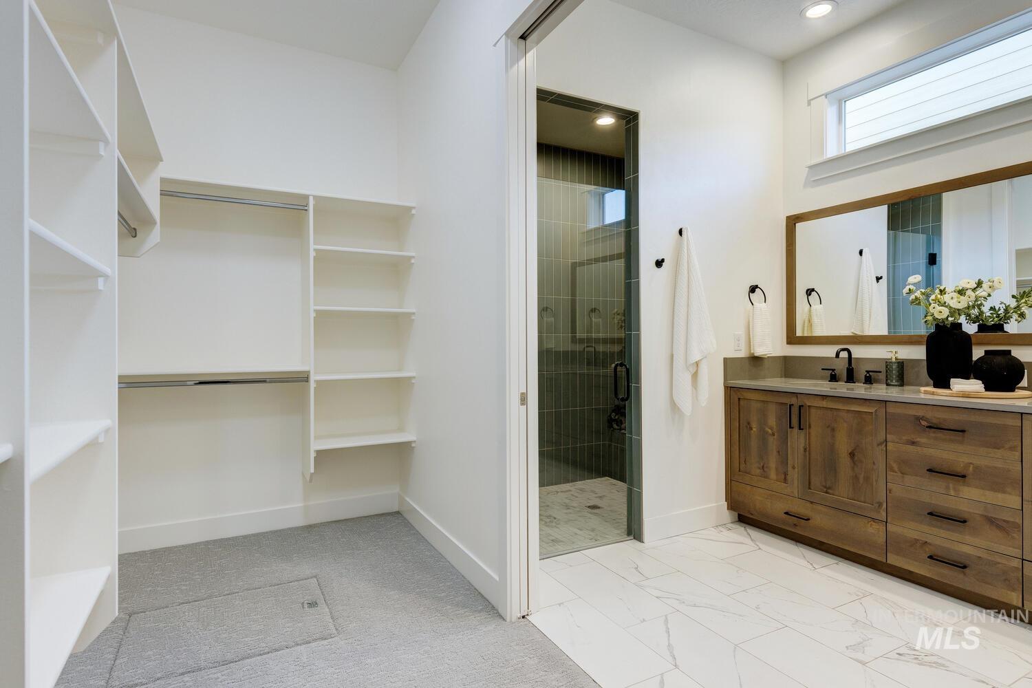 Bathroom featuring vanity, a stall shower, a walk in closet, and recessed lighting
