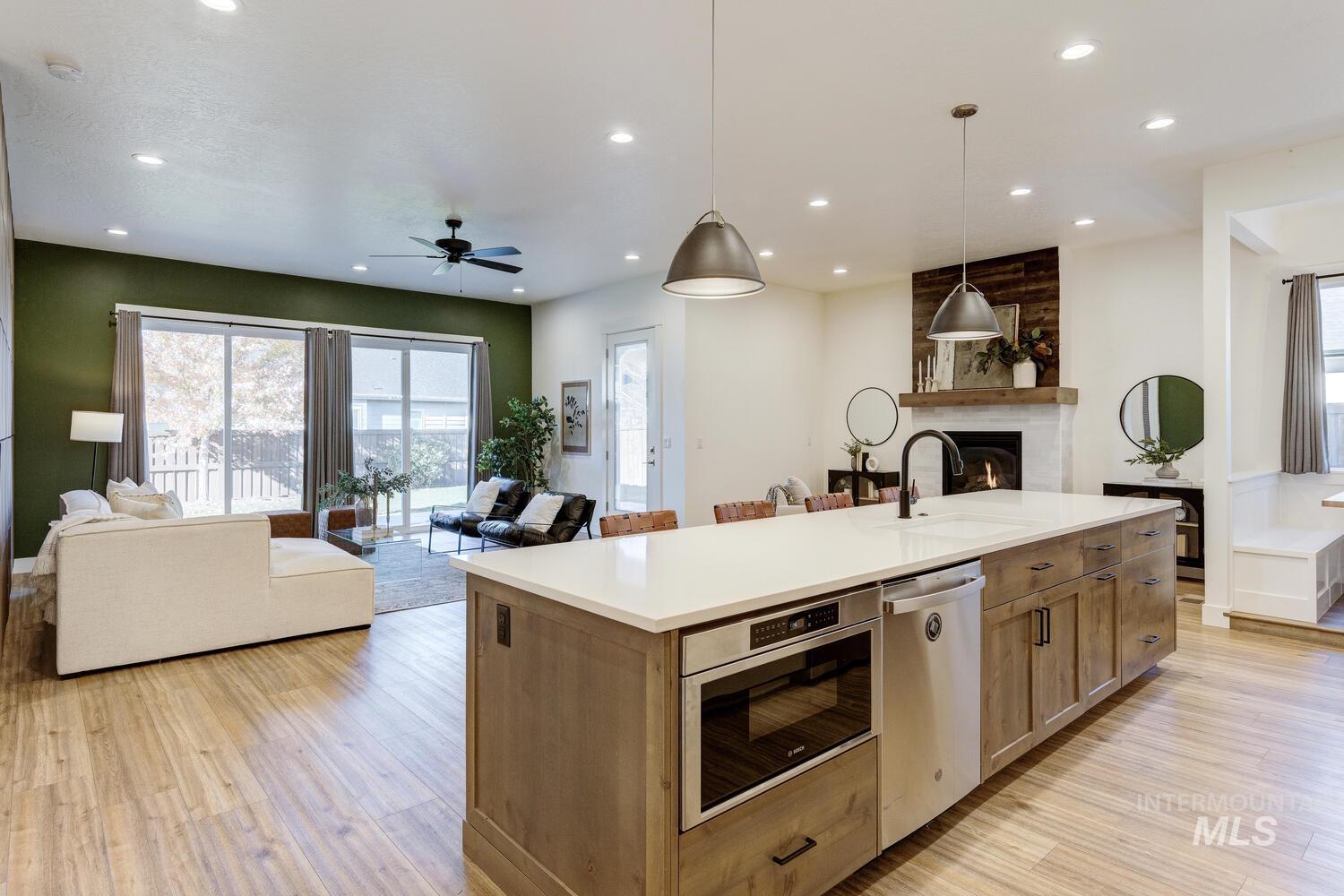 Kitchen with open floor plan, hanging light fixtures, stainless steel appliances, light wood finished floors, and recessed lighting