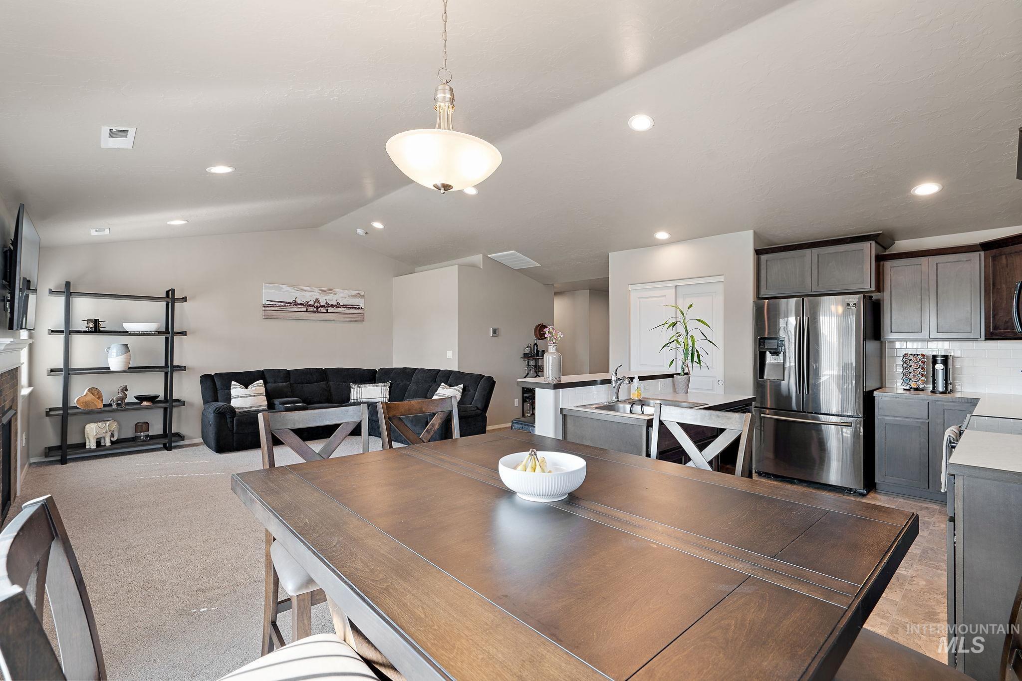 Dining space featuring vaulted ceiling, recessed lighting, a fireplace, and light colored carpet