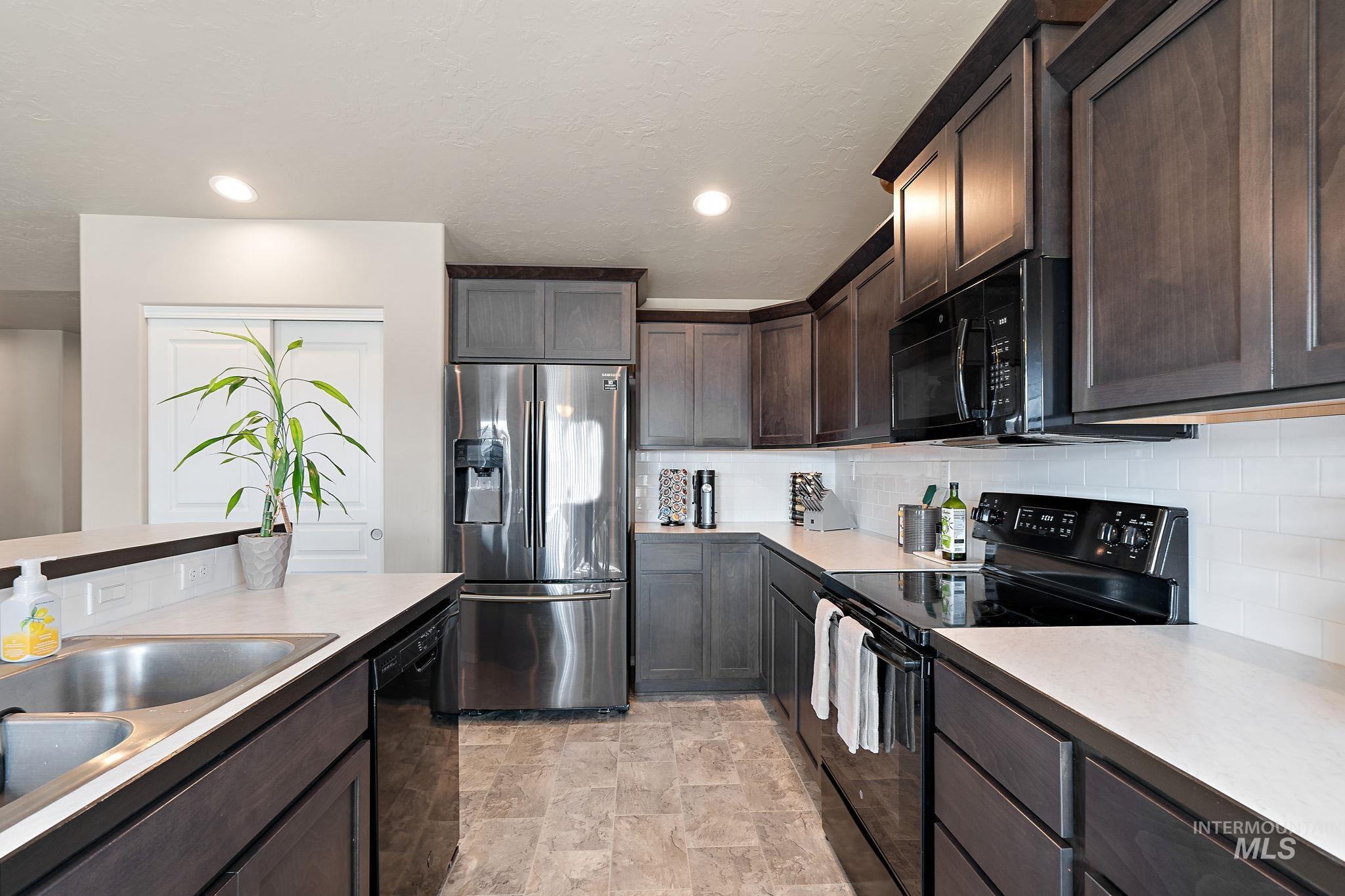 Kitchen featuring black appliances, dark brown cabinets, tasteful backsplash, light countertops, and a textured ceiling